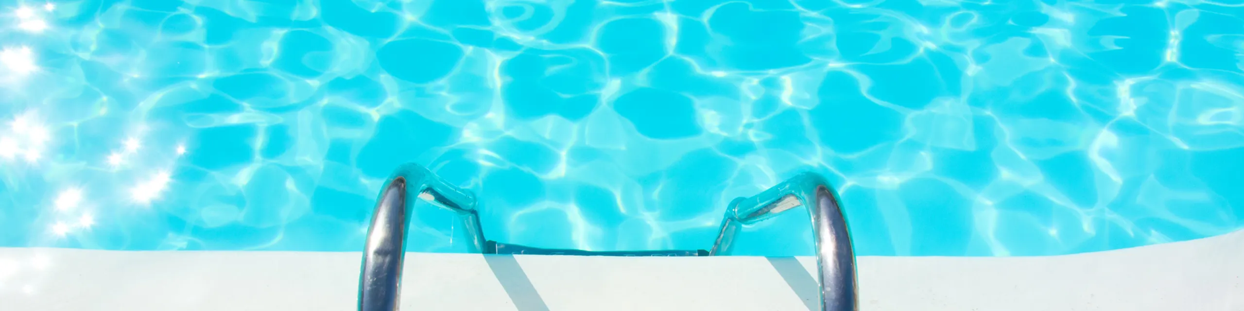 Inviting swimming pool with sparkling turquoise water and sleek metal ladder, perfect for relaxation and summer fun.