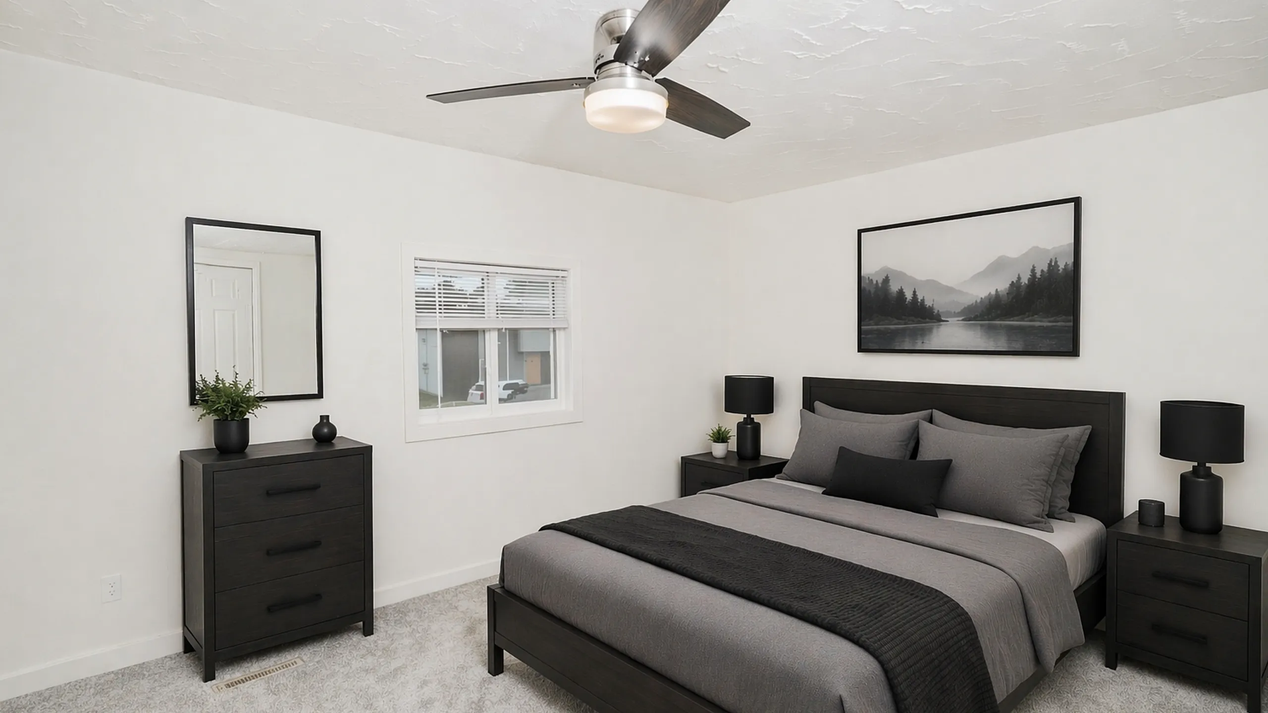Modern bedroom with dark wood bed frame, gray bedding, matching nightstands with black lamps, dresser with mirror, ceiling fan, and carpet flooring with natural light from a small window.