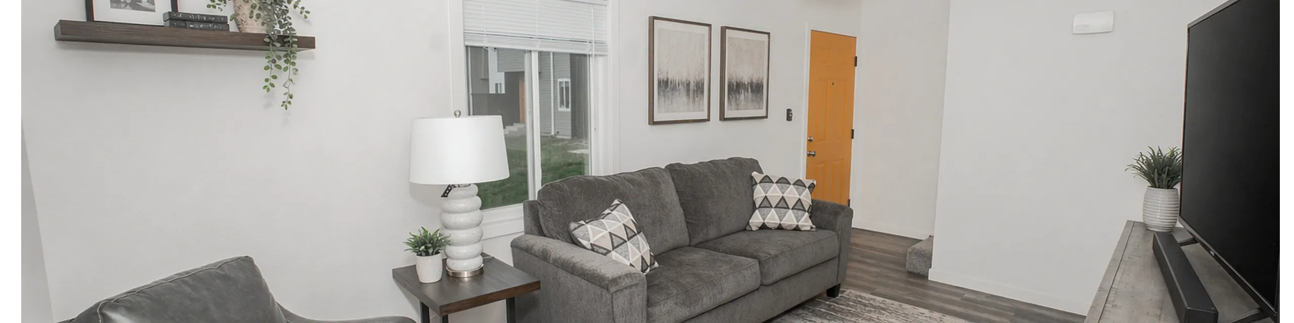 Modern living room featuring a cozy gray sofa, sleek armchair, and elegant decor with abundant natural light.