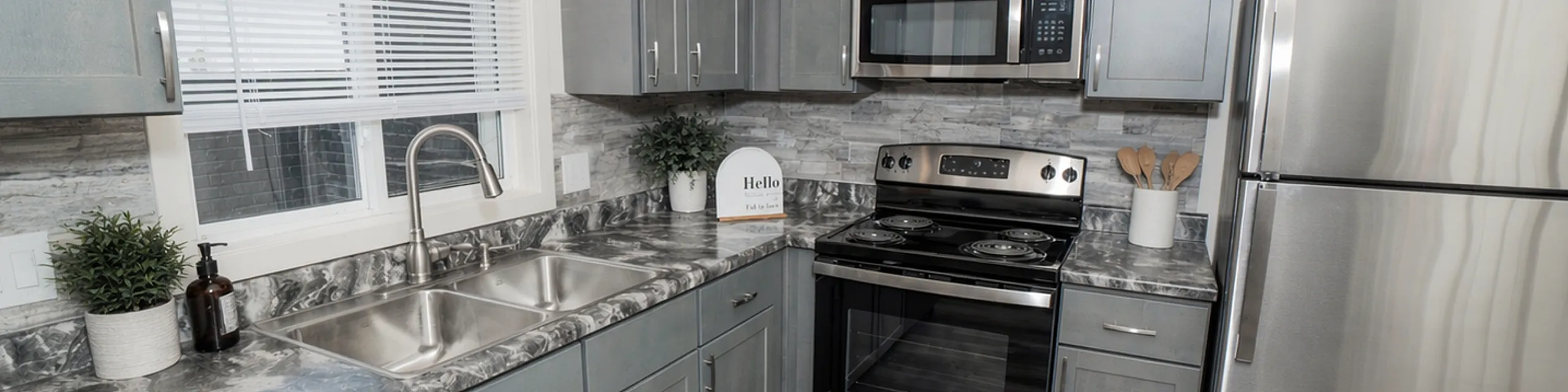 Modern kitchen with sleek stainless steel appliances and elegant grey cabinetry, featuring a stylish marble countertop and contemporary flooring.
