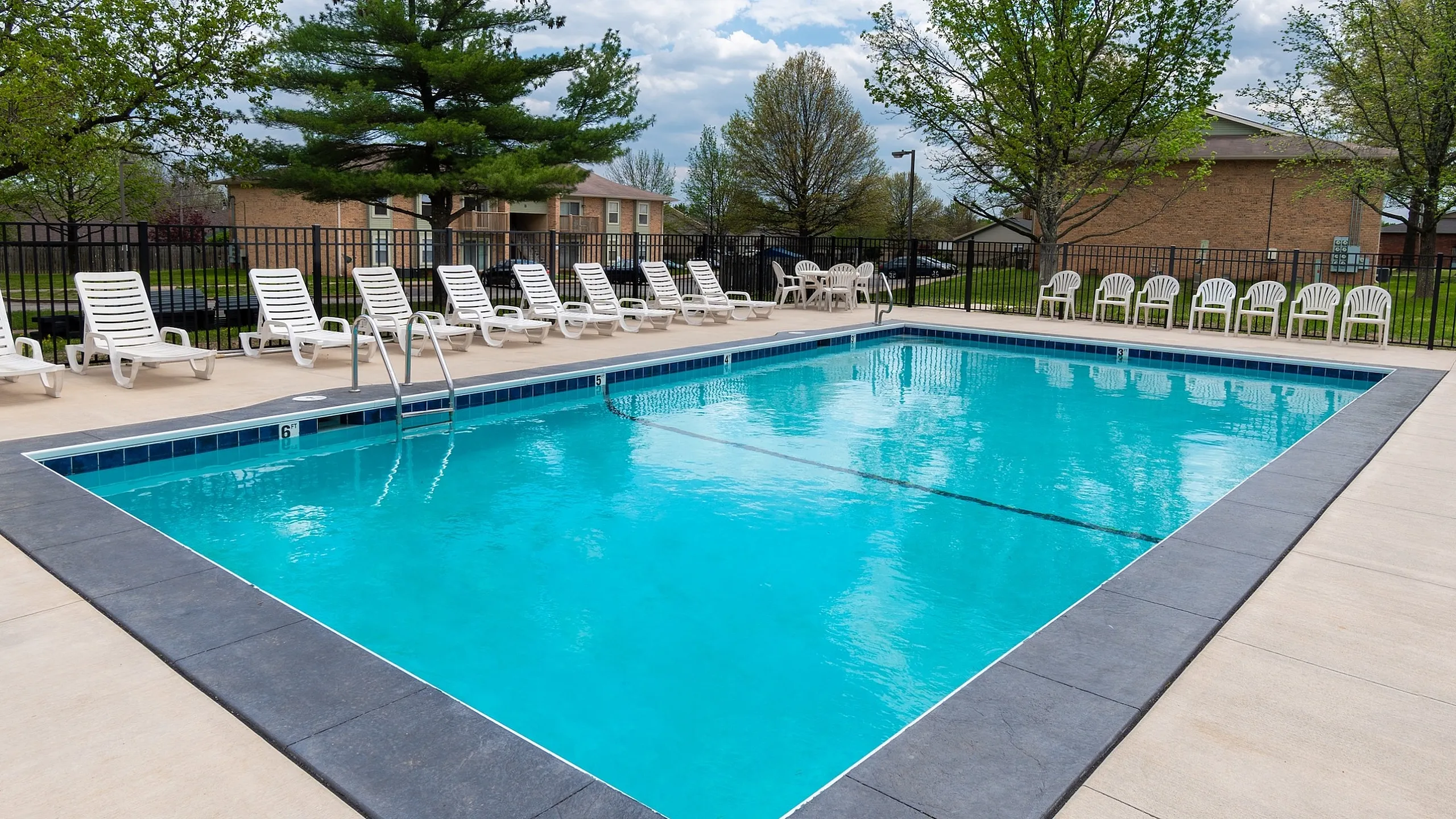 Inviting outdoor swimming pool surrounded by lush trees and comfortable lounge chairs, perfect for relaxation.