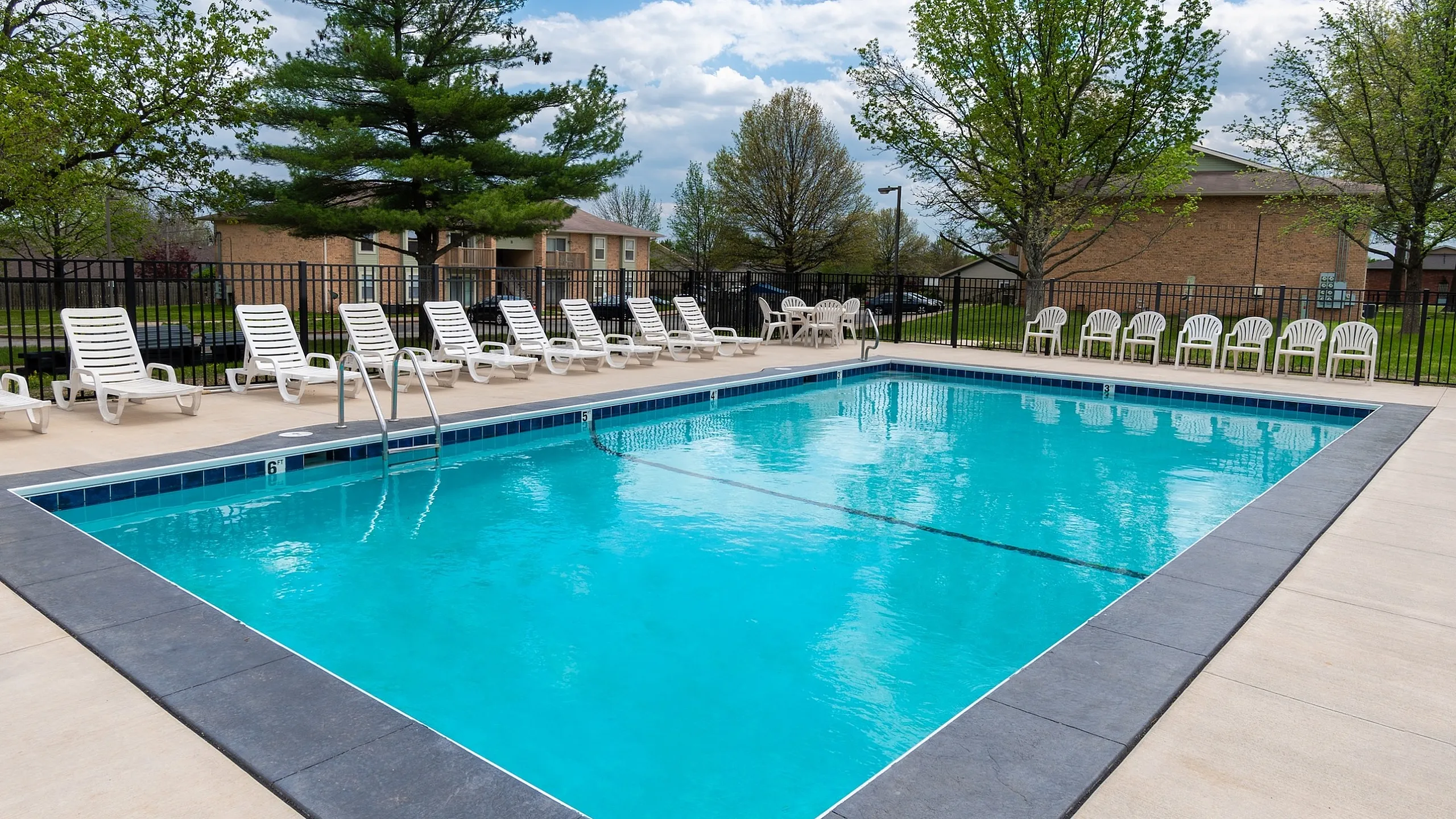 Inviting outdoor pool area with crystal clear water, surrounded by comfortable lounge chairs and lush greenery.