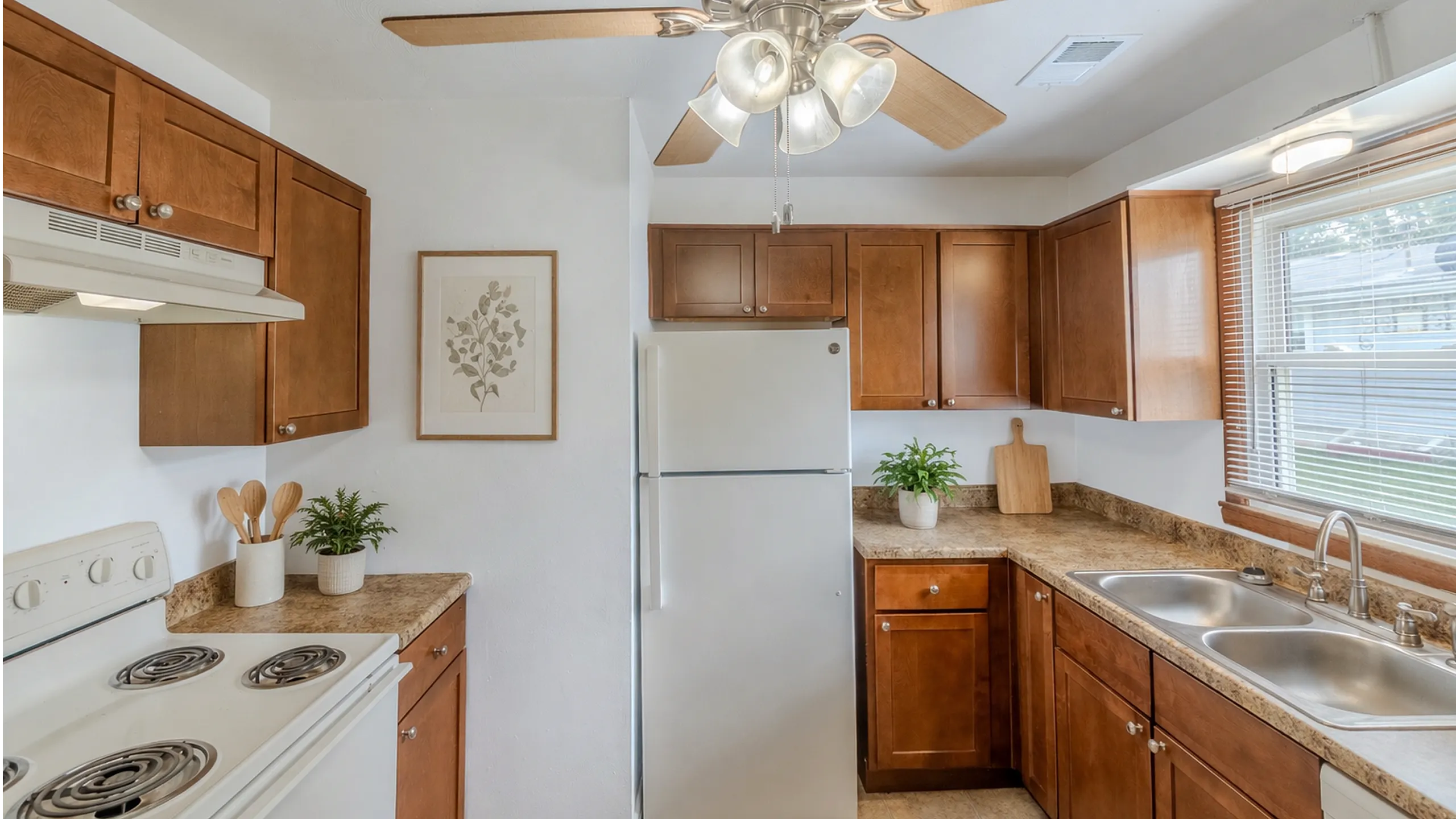 Charming kitchen with modern light fixture, wooden cabinets, and ample natural light, perfect for culinary creativity.
