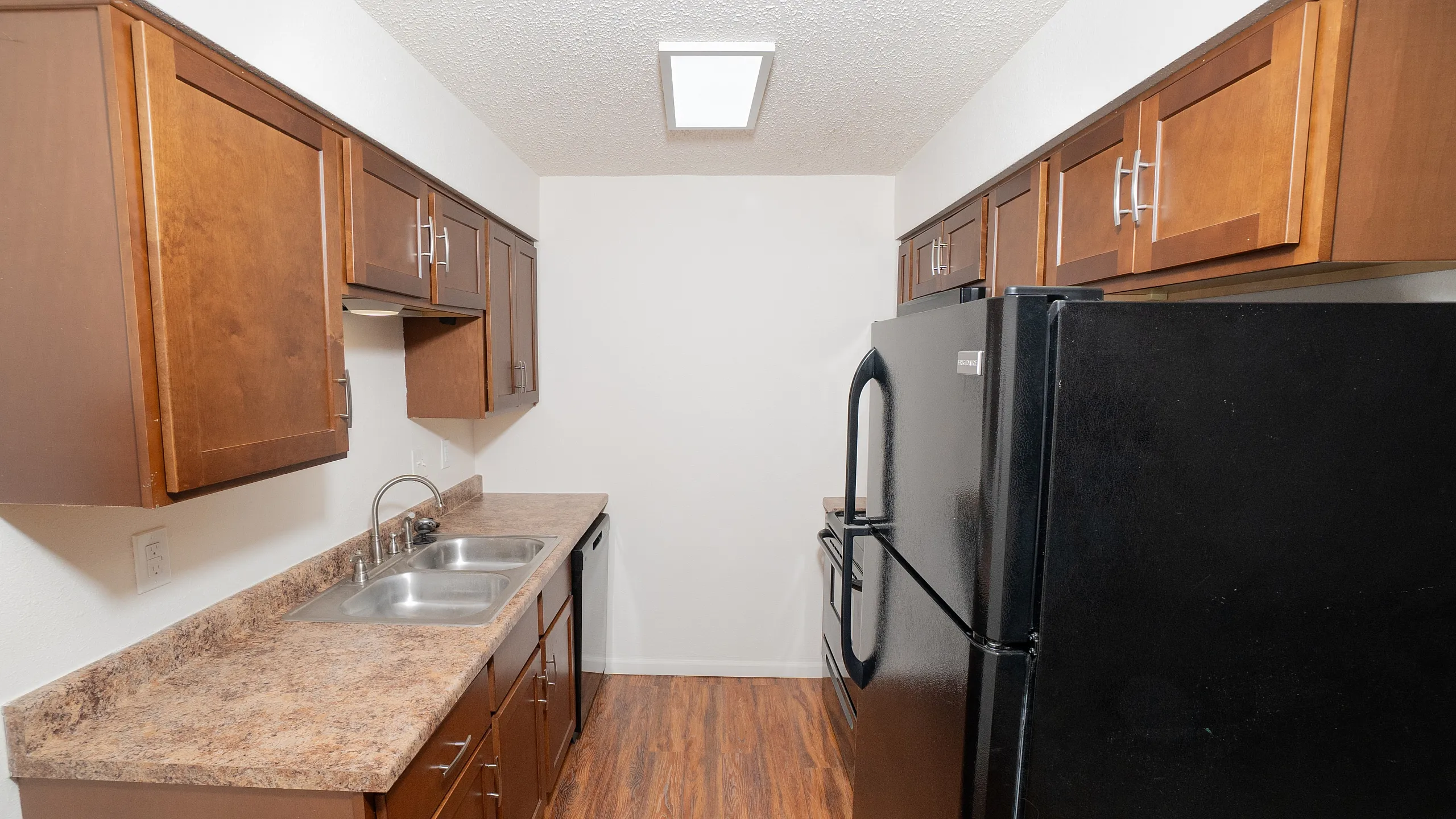 Modern kitchen with sleek dark appliances, elegant wooden cabinetry, and a stylish laminate floor.