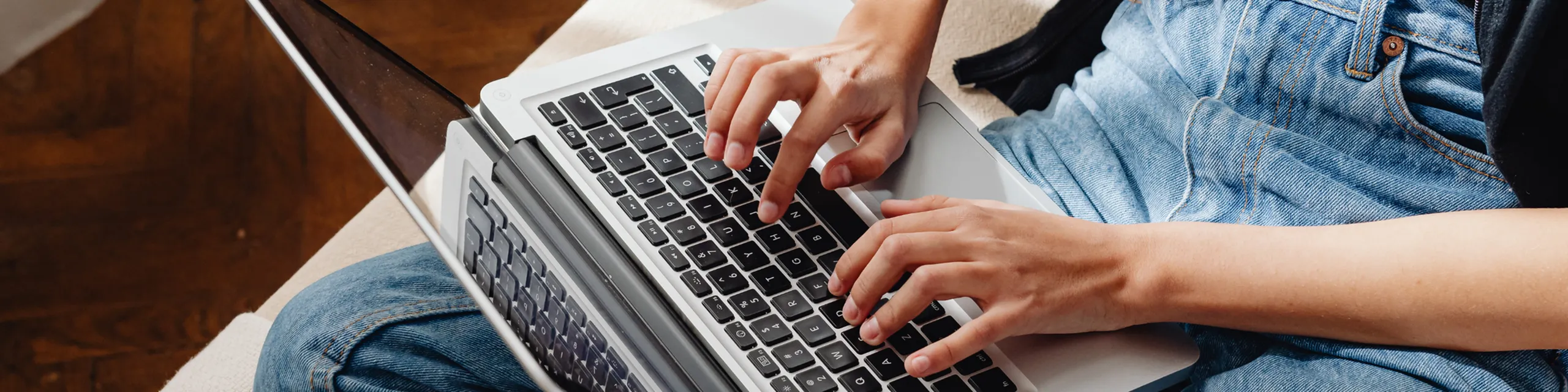 Person typing on a laptop, seated comfortably on a couch, showcasing an inviting atmosphere for work from home.