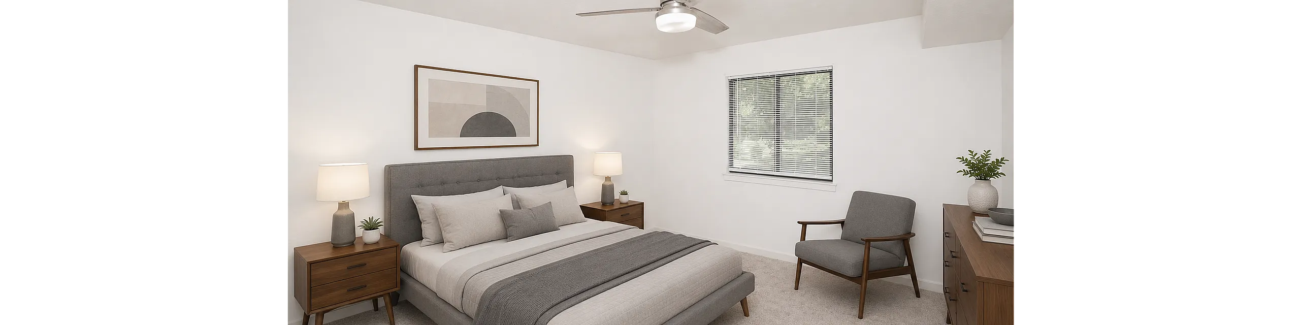 Inviting bedroom with a modern grey upholstered bed, matching mid-century nightstands, and a cozy armchair, accented by natural light and elegant decor.