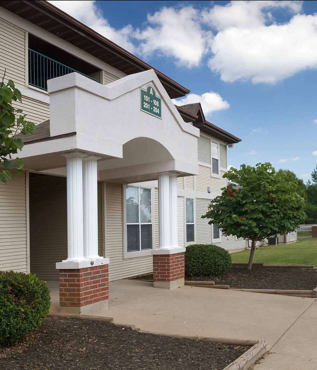 Charming apartment building with classic architectural details, lush greenery, and a welcoming entrance.
