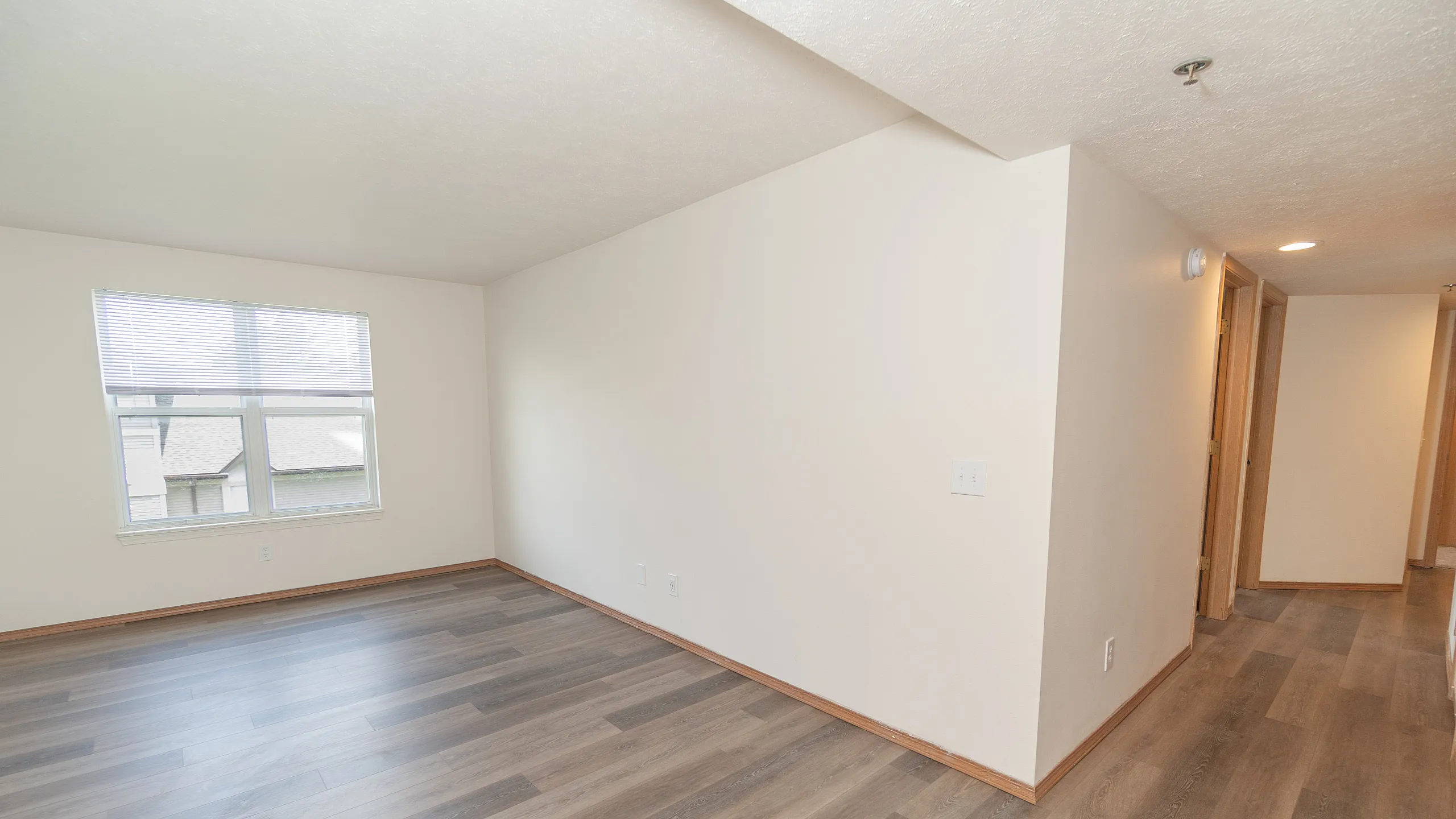 Inviting apartment space featuring elegant wood flooring and abundant natural light from large windows.