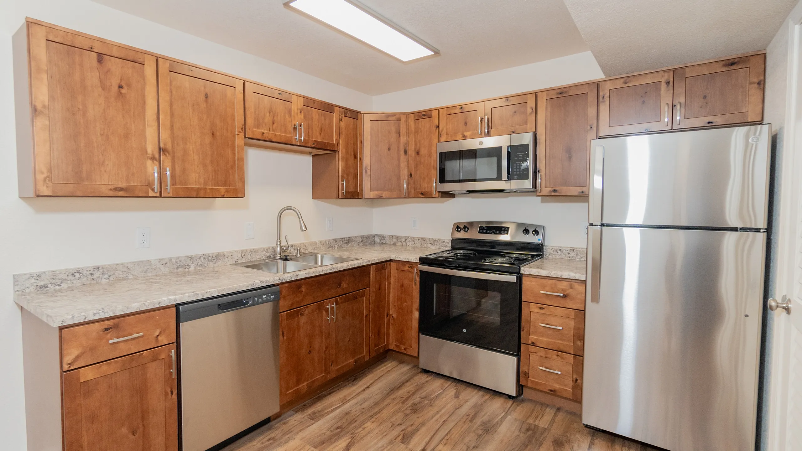 Modern kitchen with stainless steel appliances, wooden cabinetry, and elegant countertops in a cozy apartment.
