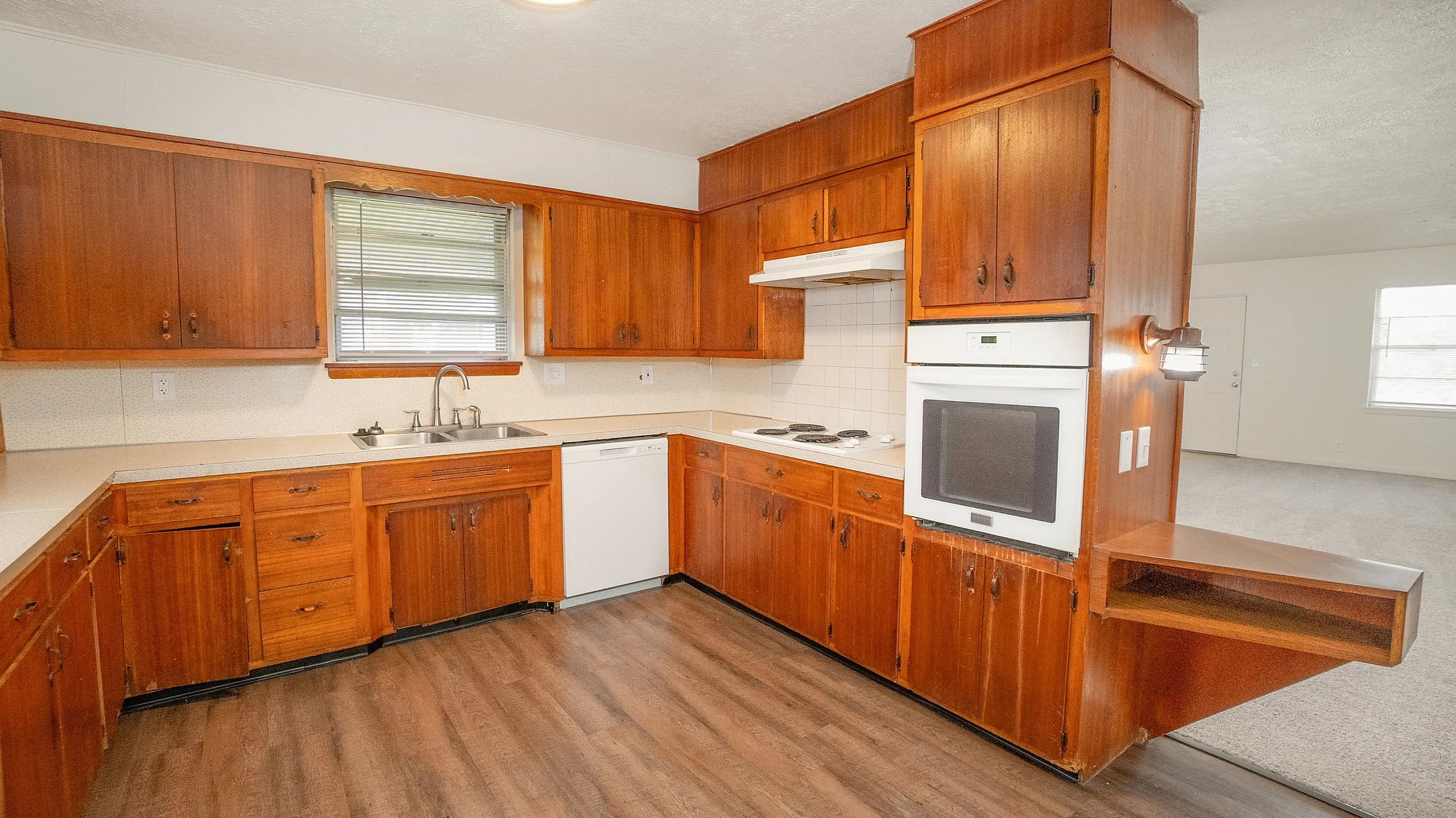Charming kitchen with rich wooden cabinets, modern appliances, and warm lighting, seamlessly connected to a cozy living area.