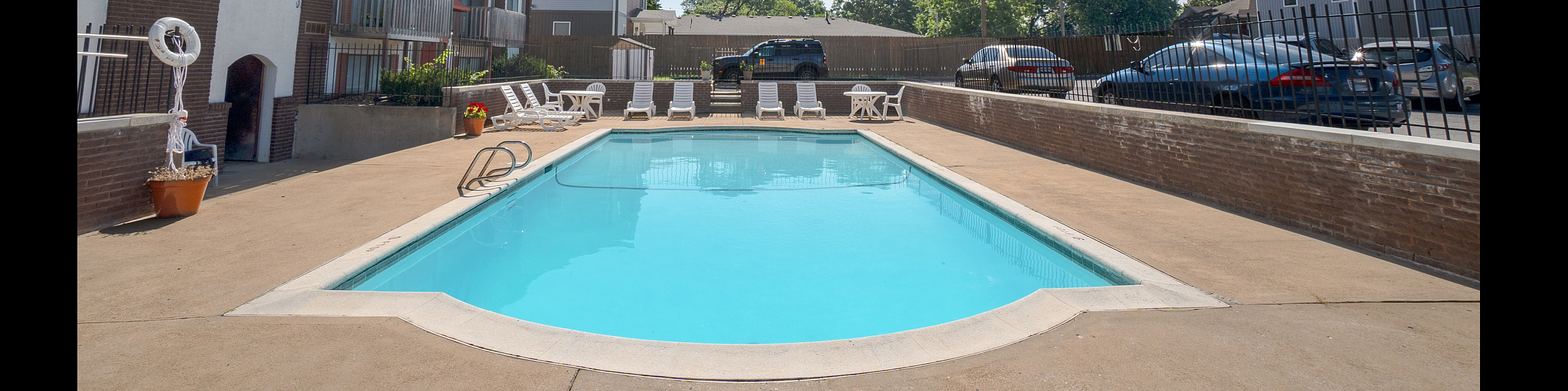 Inviting apartment complex with a sunlit swimming pool, surrounded by relaxed seating and modern architecture.