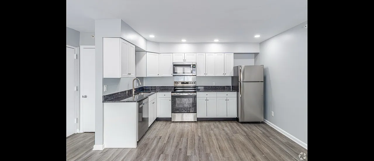 Contemporary kitchen with sleek white cabinetry, stainless steel appliances, and elegant countertops, complemented by stylish wood flooring.