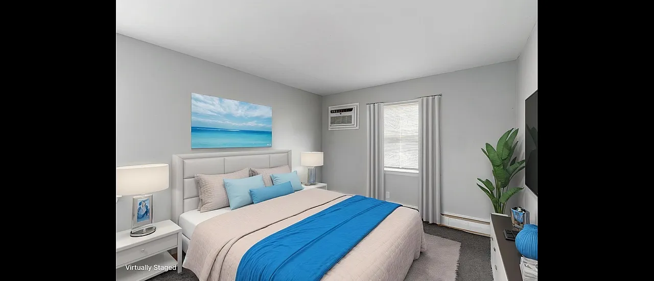 Beautifully staged bedroom featuring a plush bed with vibrant blue accents, serene ocean artwork, and modern decor.