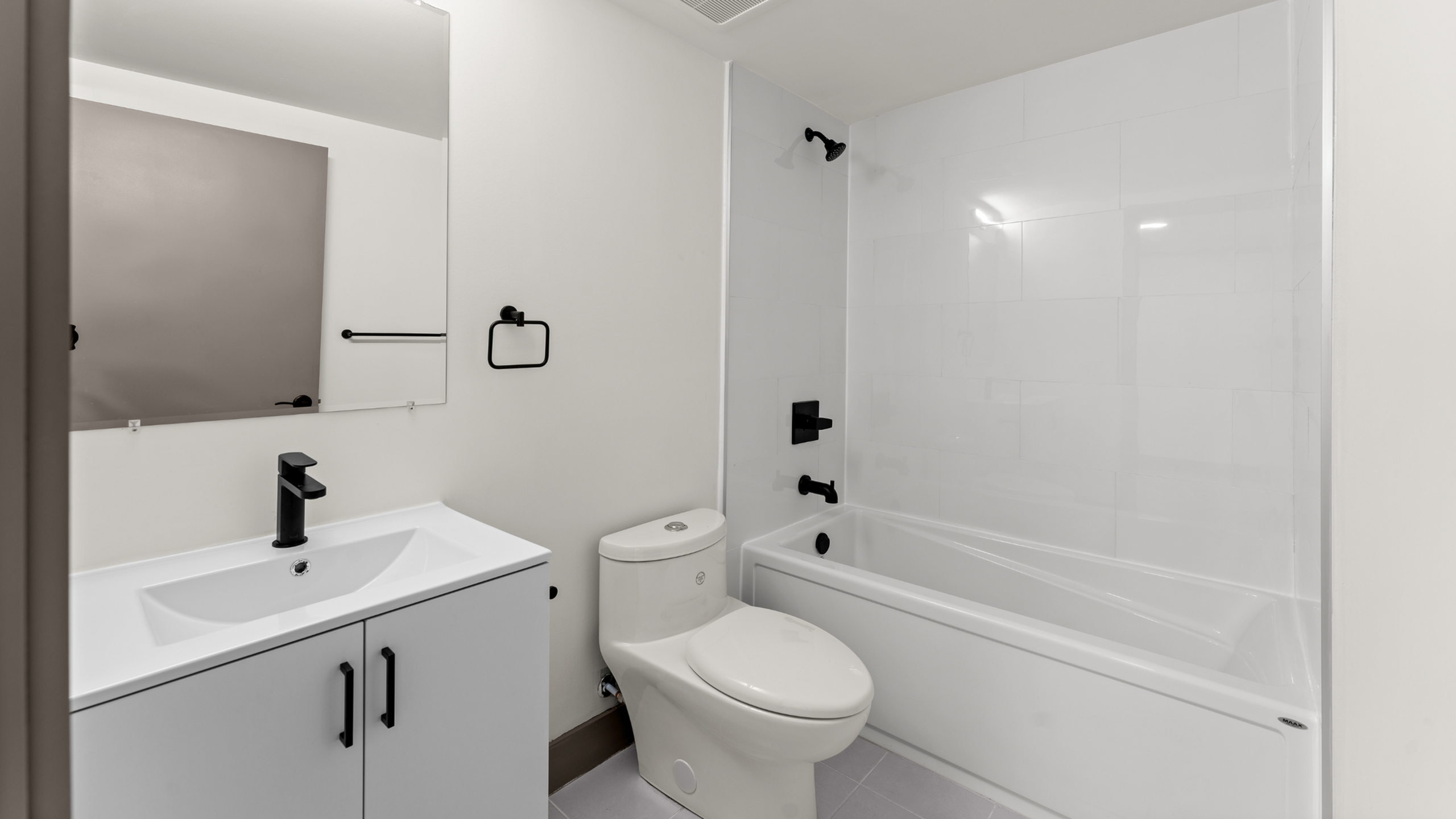 Modern bathroom featuring sleek black fixtures, a spacious bathtub, and elegant tile work.