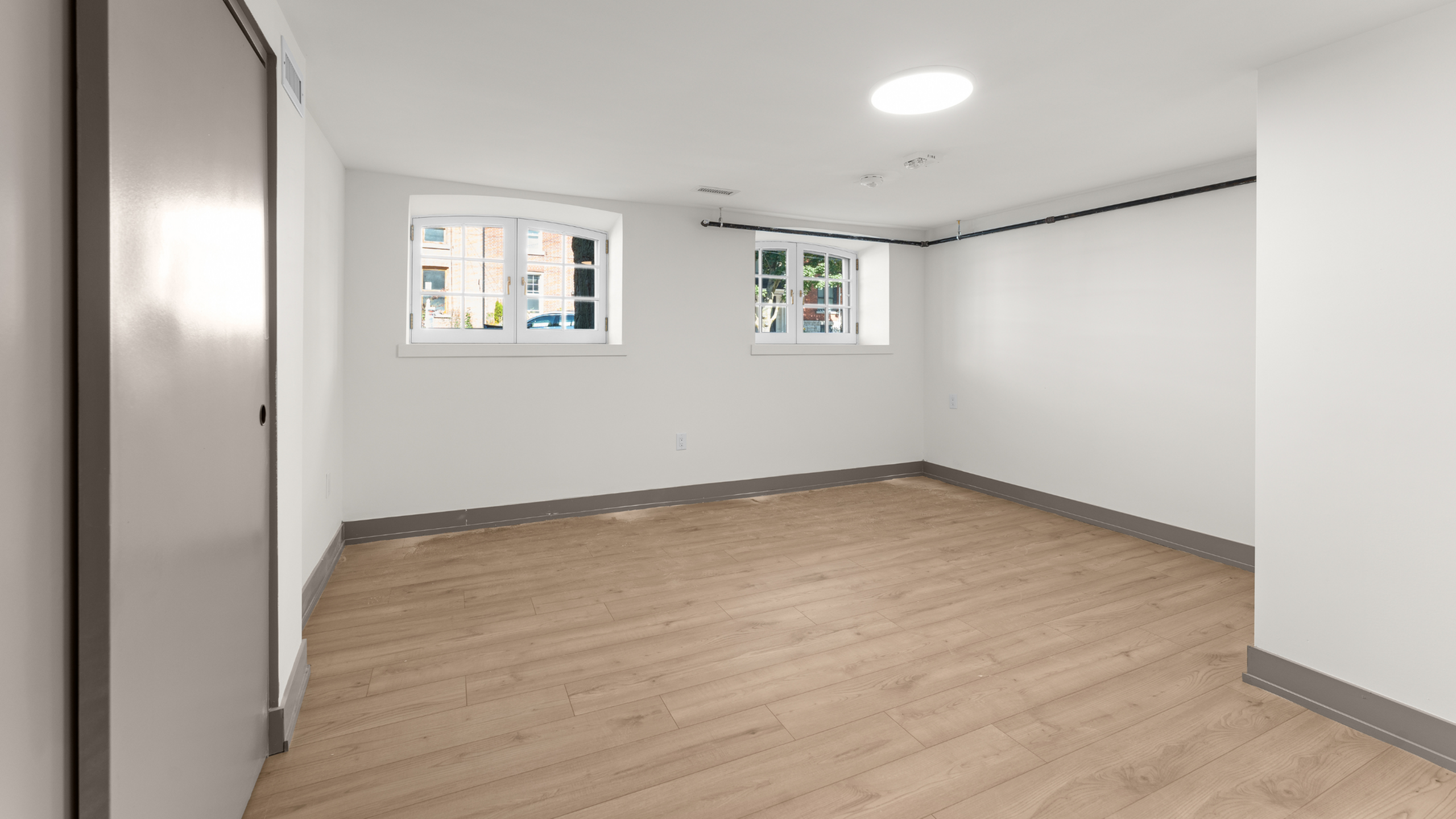 Bright room with elegant wood flooring and ample natural light from stylish windows.