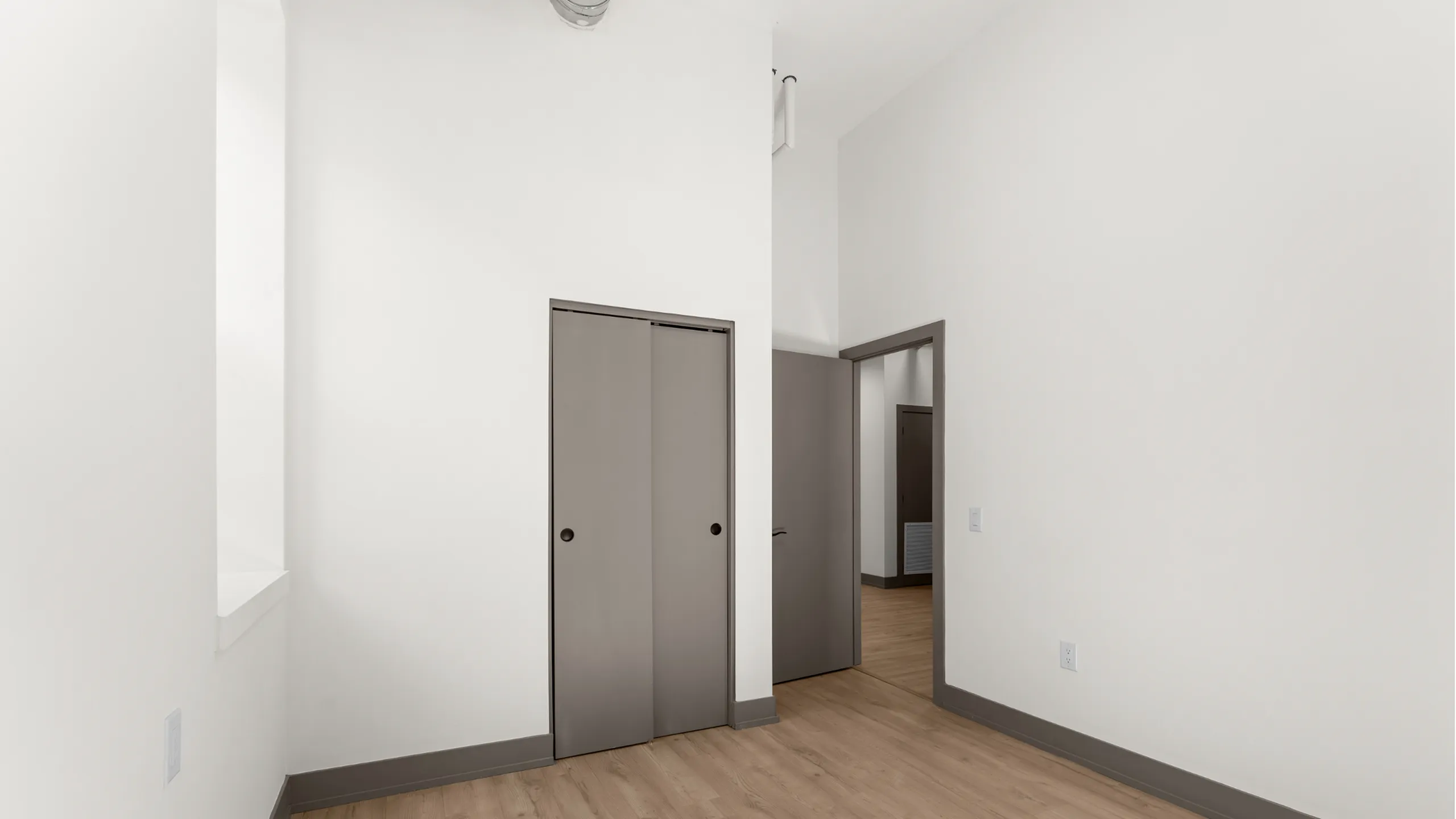 Bright and spacious room with elegant hardwood flooring and sliding closet doors, perfect for a modern minimalist style.