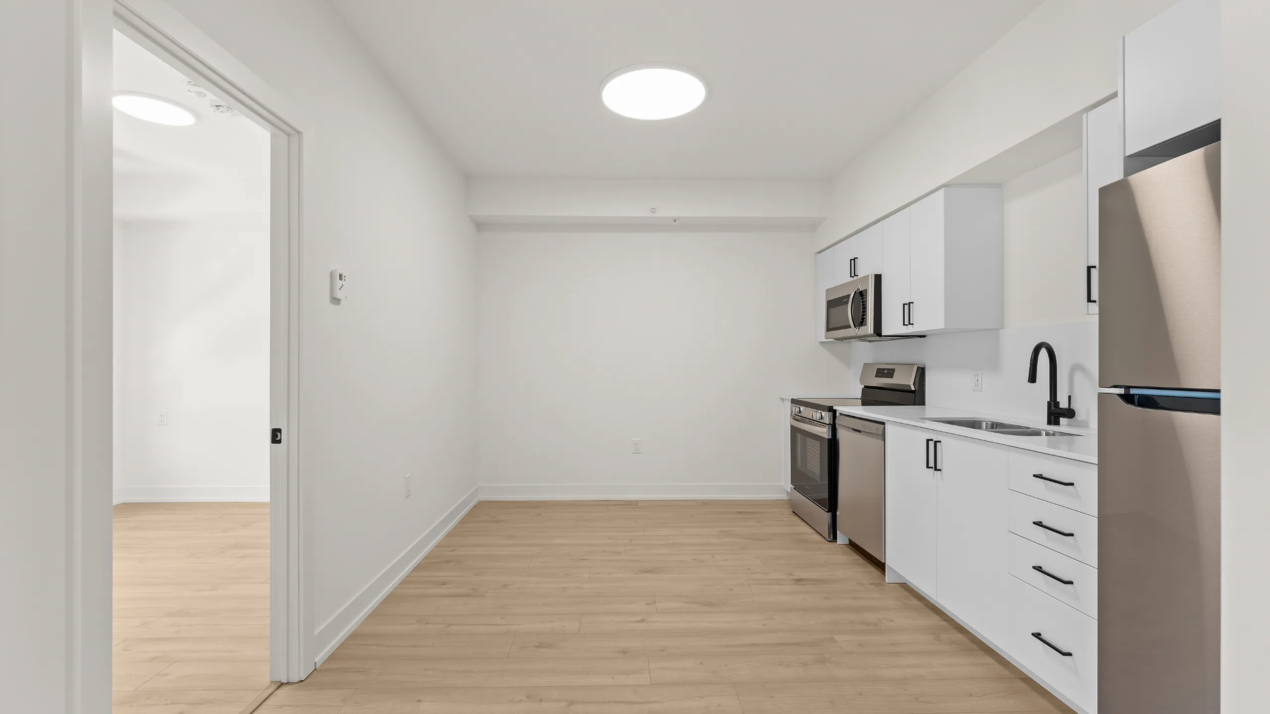 Modern kitchen with sleek stainless steel appliances, white cabinetry, and elegant hardwood flooring.