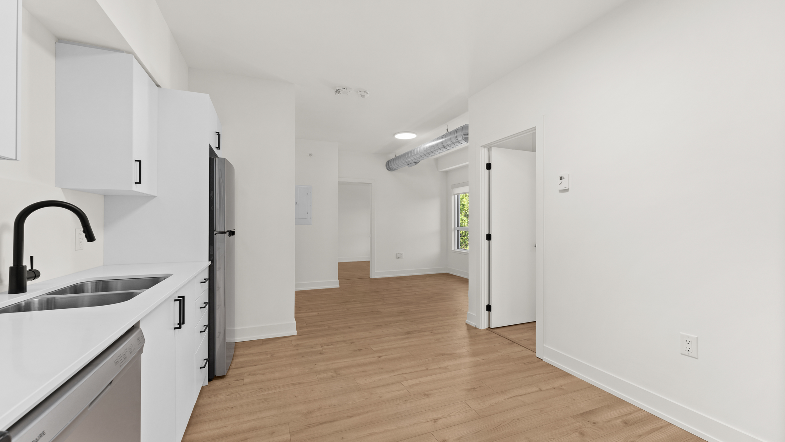 Bright and modern kitchen with sleek white cabinetry, stainless steel appliances, and natural wood flooring.
