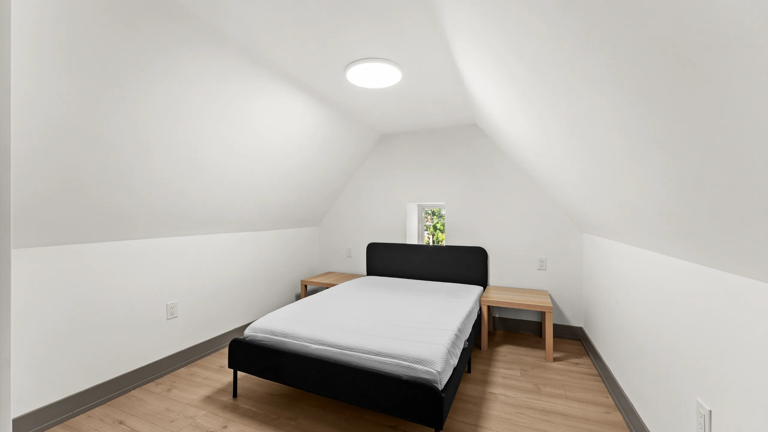Cozy attic bedroom with a sleek modern bed, natural wood side tables, and a minimalist aesthetic.