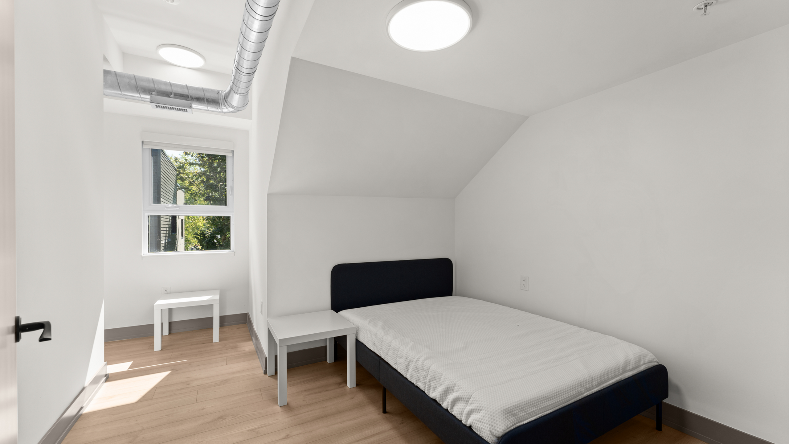 Bright and modern bedroom with stylish minimalist decor, featuring a cozy single bed under a large window for ample natural light.