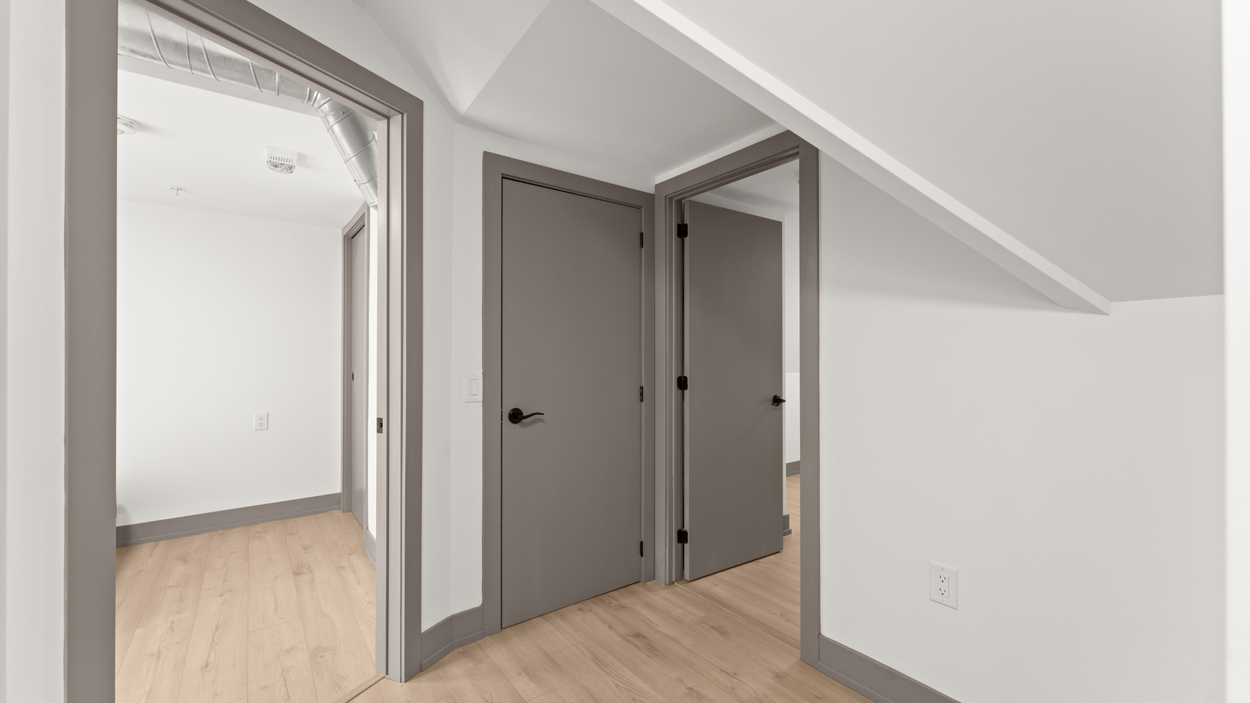 Modern hallway featuring sleek gray doors with a minimalist design and light wooden flooring, offering a clean and inviting atmosphere.