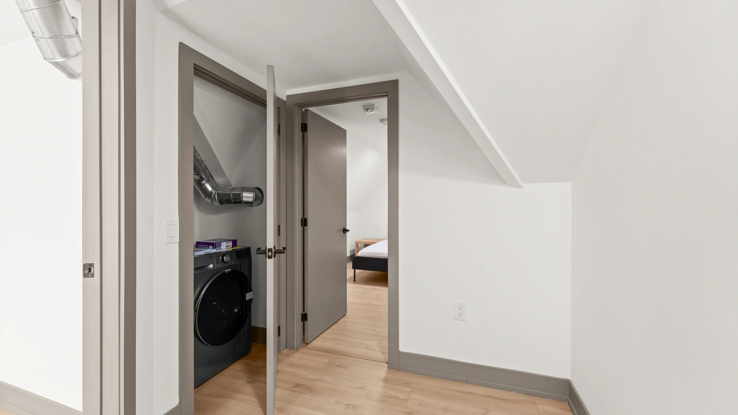 Cozy hallway with sleek laundry nook and bright bedroom entrance, showcasing modern design and functionality.