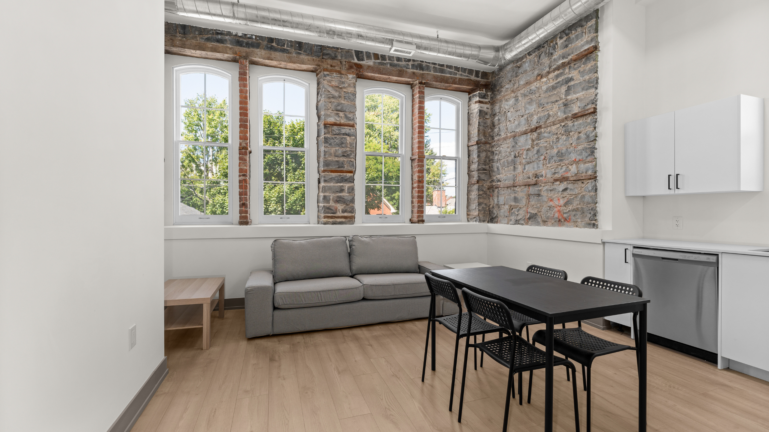 Charming loft-style apartment with exposed brick walls, large arched windows, and a cozy open-concept living area.