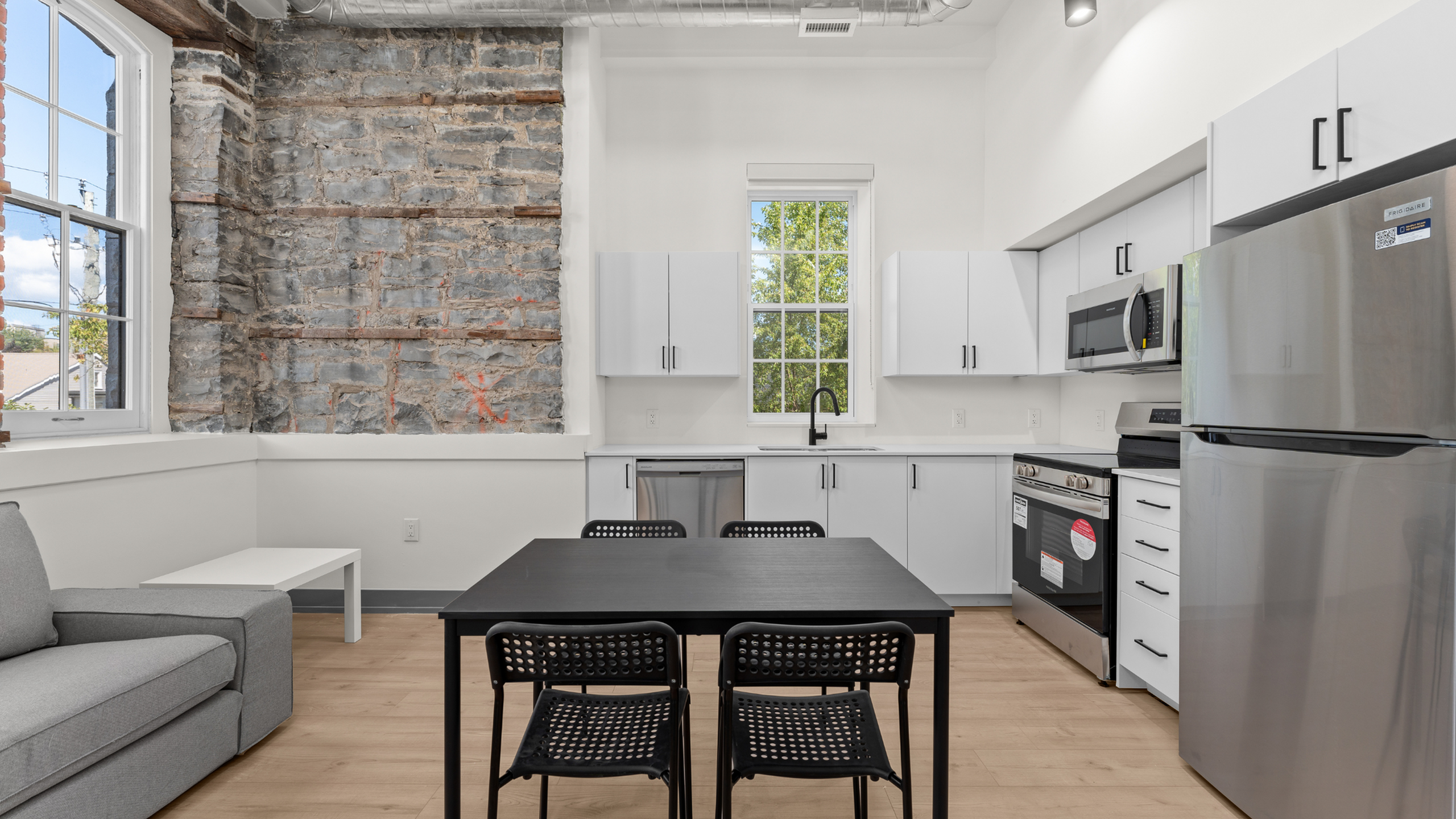 Bright, modern kitchen with sleek white cabinetry, stainless steel appliances, and exposed brick for a rustic charm.