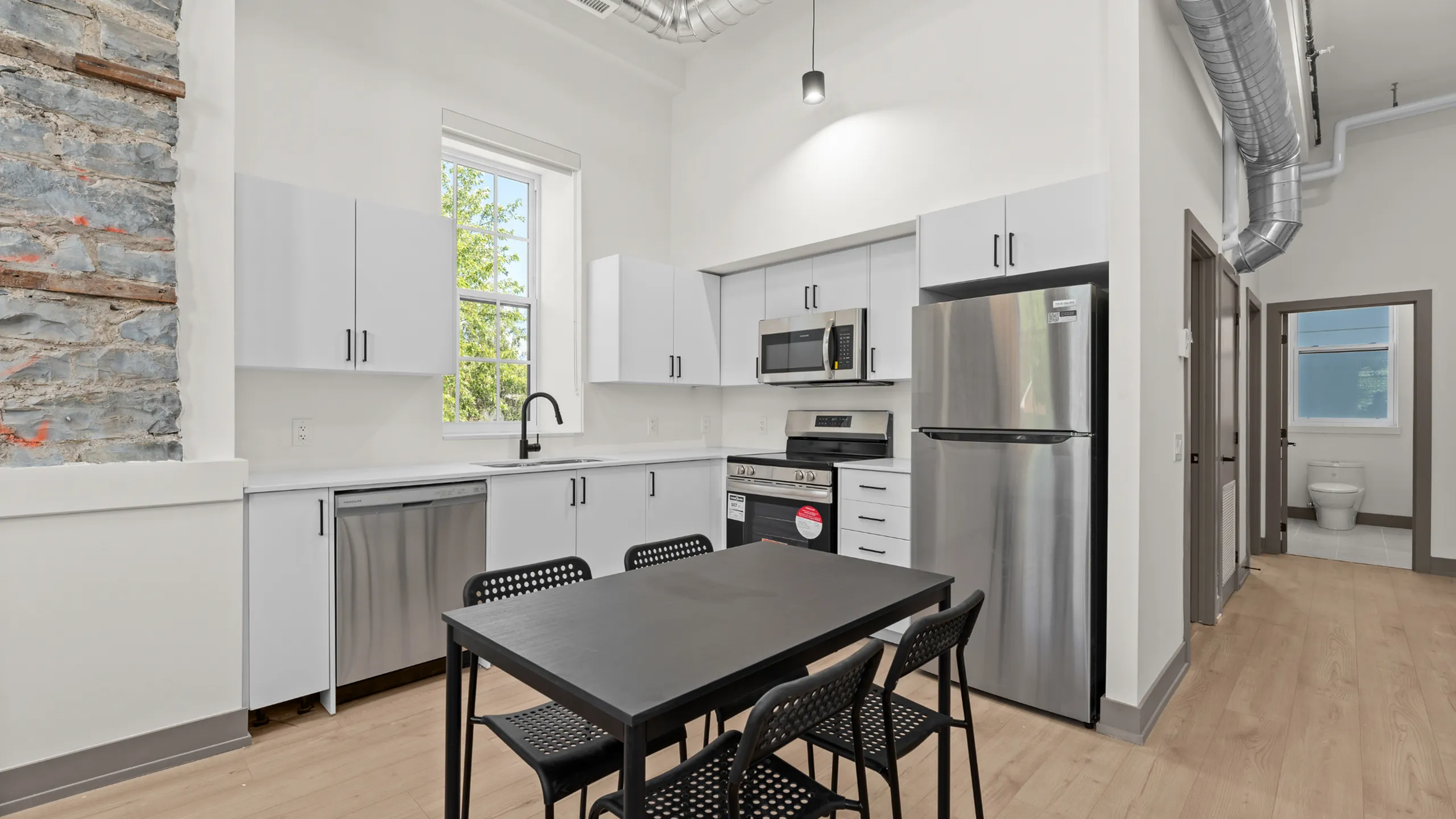 Modern kitchen with sleek white cabinetry, stainless steel appliances, and a stylish dining area, perfect for urban living.