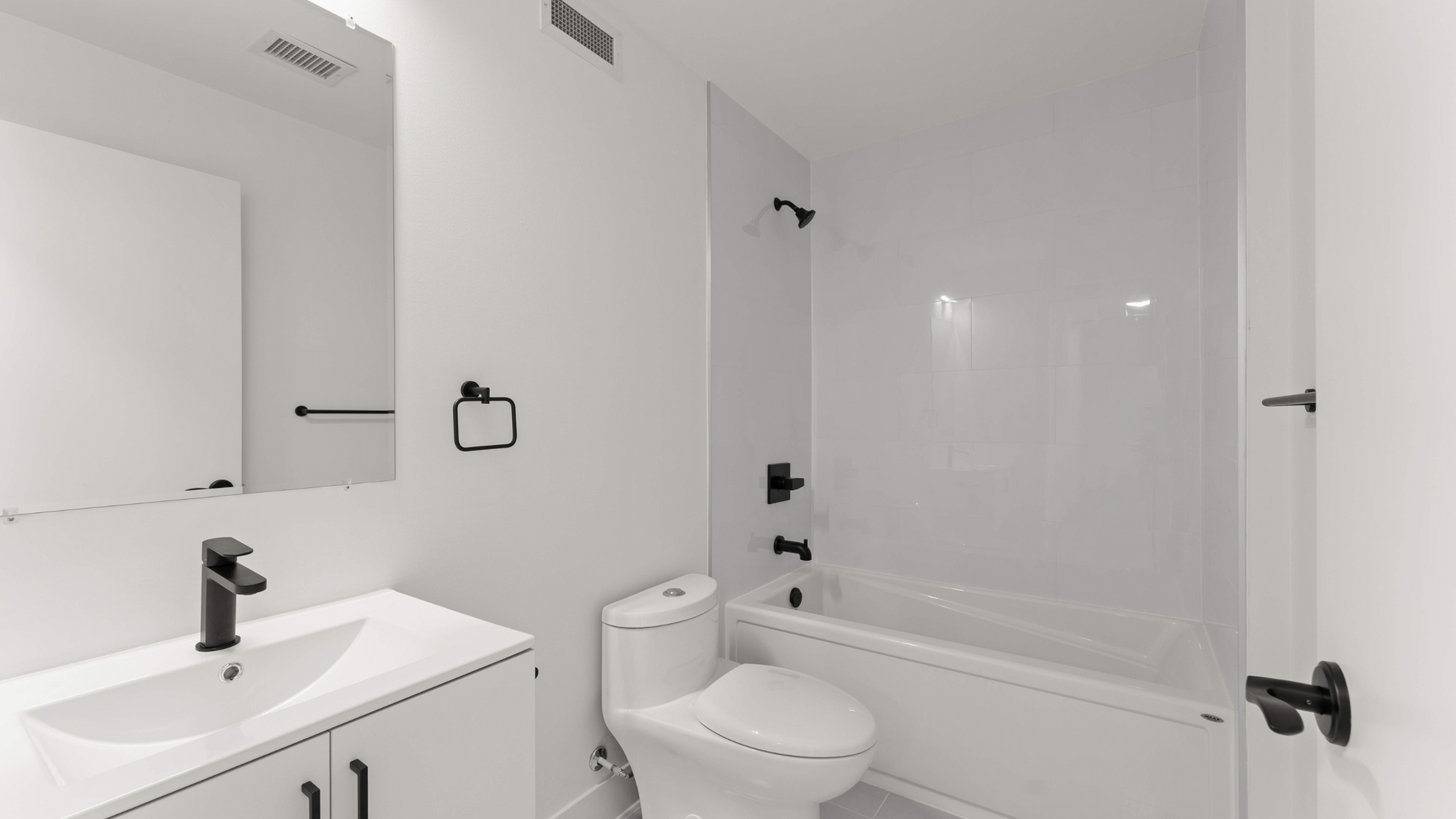 Modern bathroom with sleek black fixtures, elegant white vanity, and a spacious bathtub.