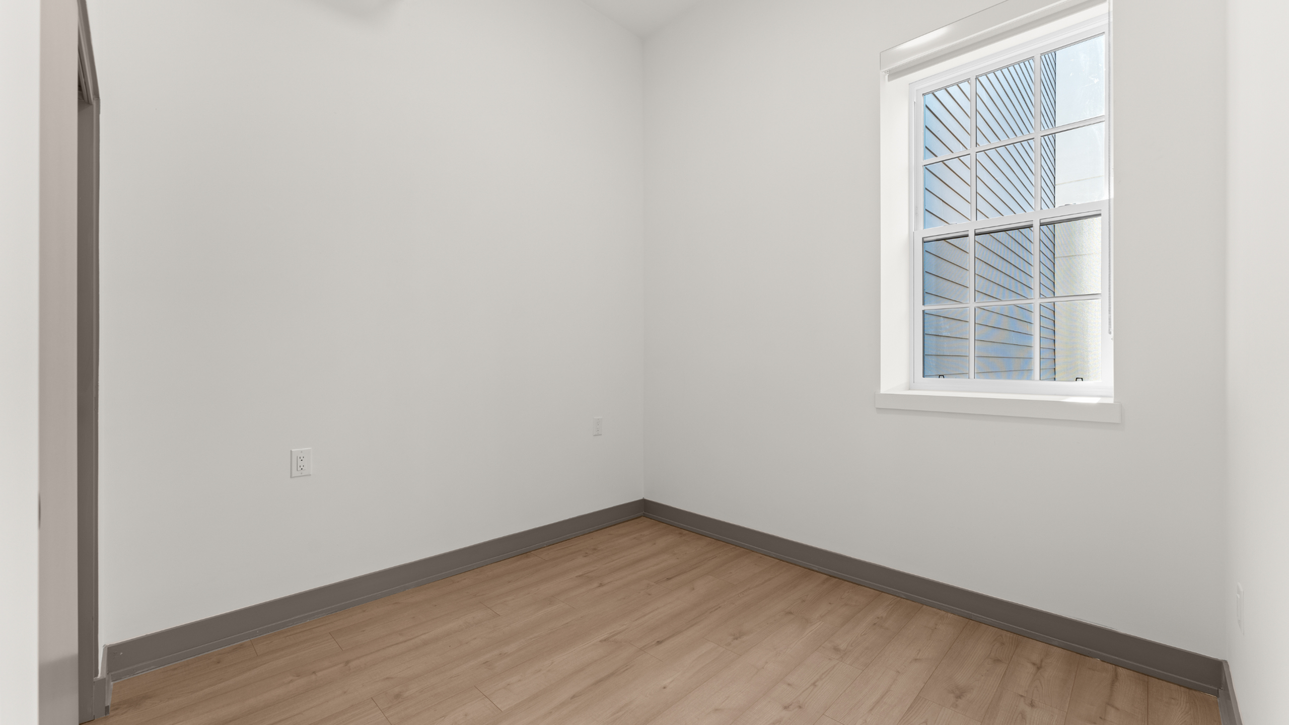 Bright, cozy room with natural light and elegant wood flooring, perfect for a small office or nursery.