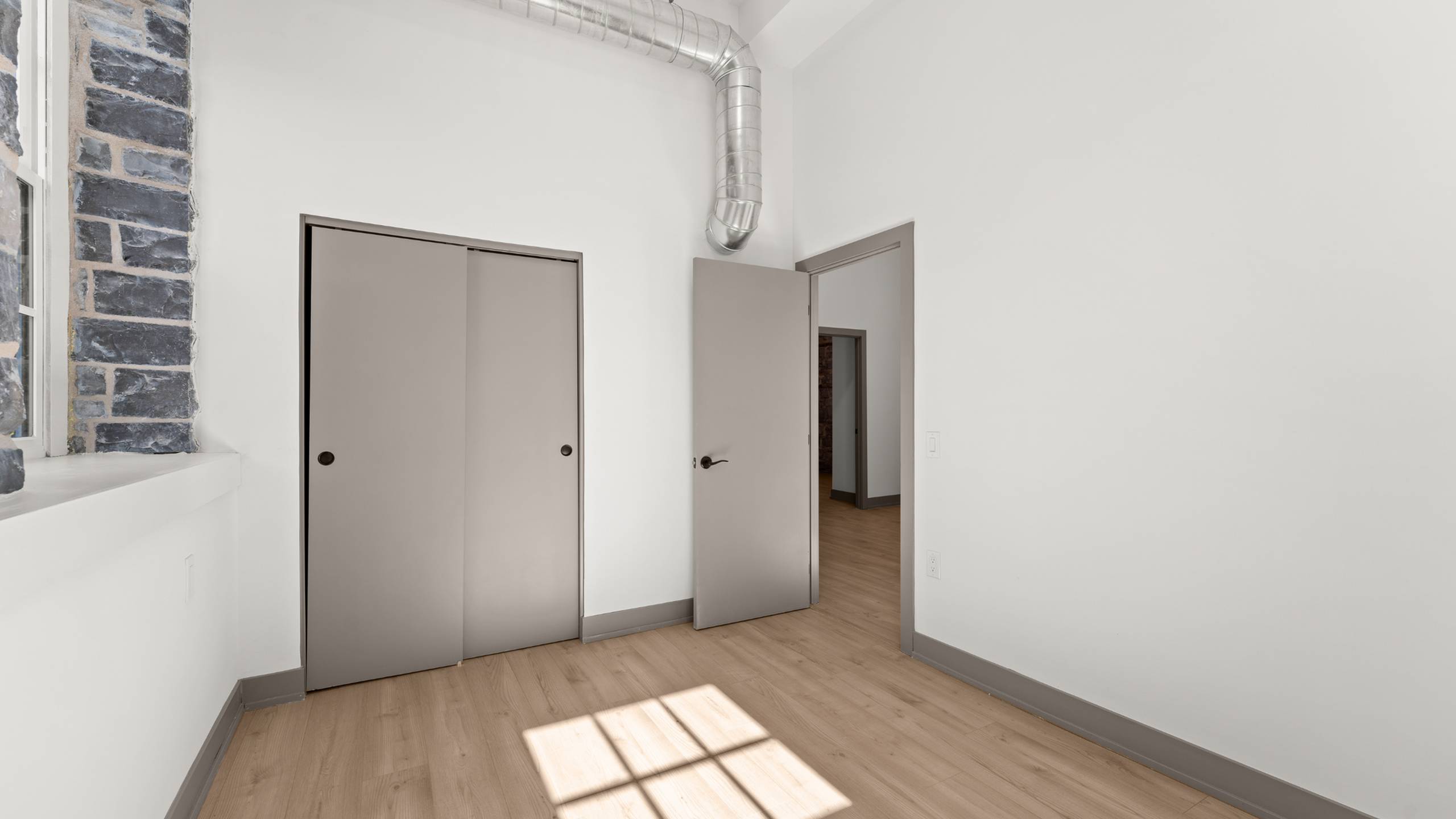 Contemporary room with smooth hardwood floors, minimalist design, and exposed brick detail offering an industrial-chic vibe.