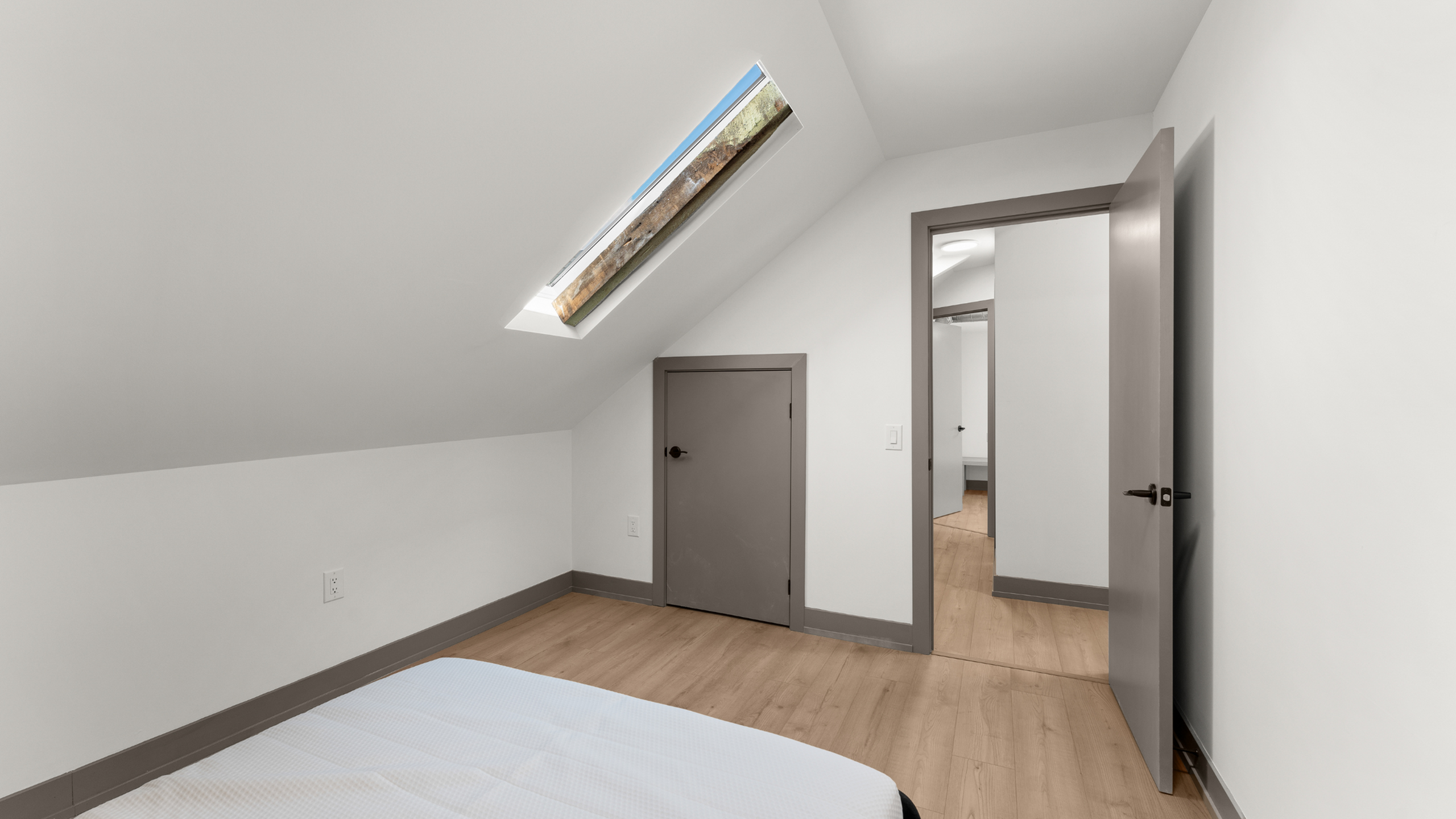 Bright attic space with a skylight, wooden floors, and minimalist design; perfect for cozy living.