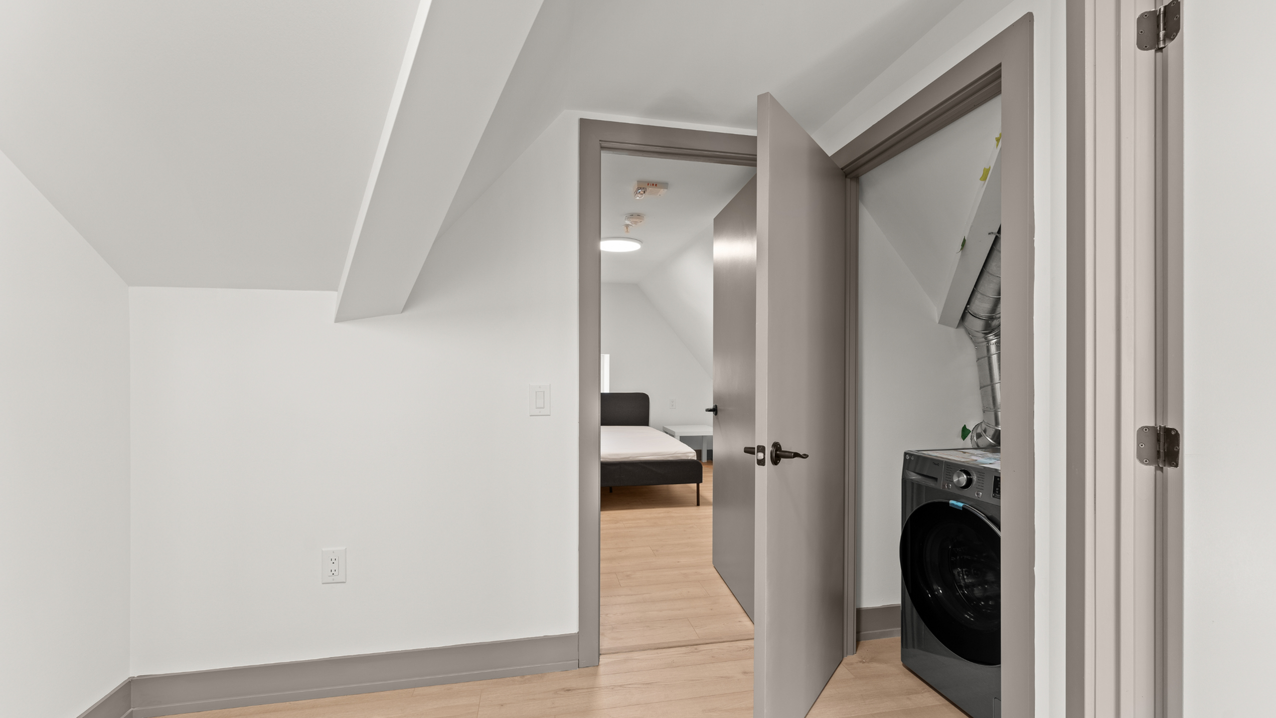 Bright attic space with a modern laundry area and cozy bedroom access.