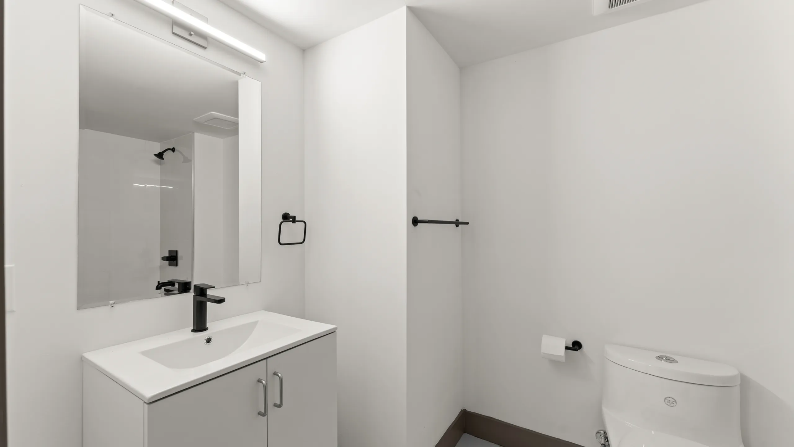 Modern bathroom with sleek black fixtures, large mirror, and elegant white vanity.