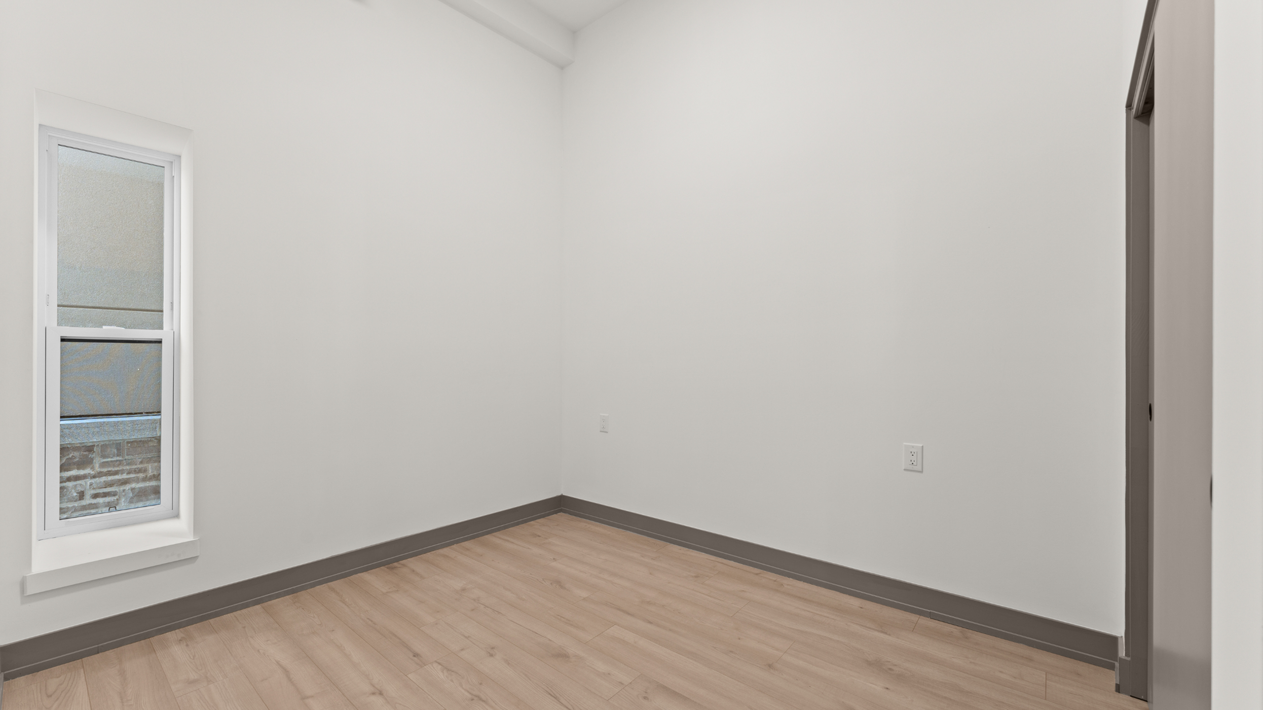 Bright and airy white-walled room featuring elegant hardwood flooring, perfect for customization and personal touch.