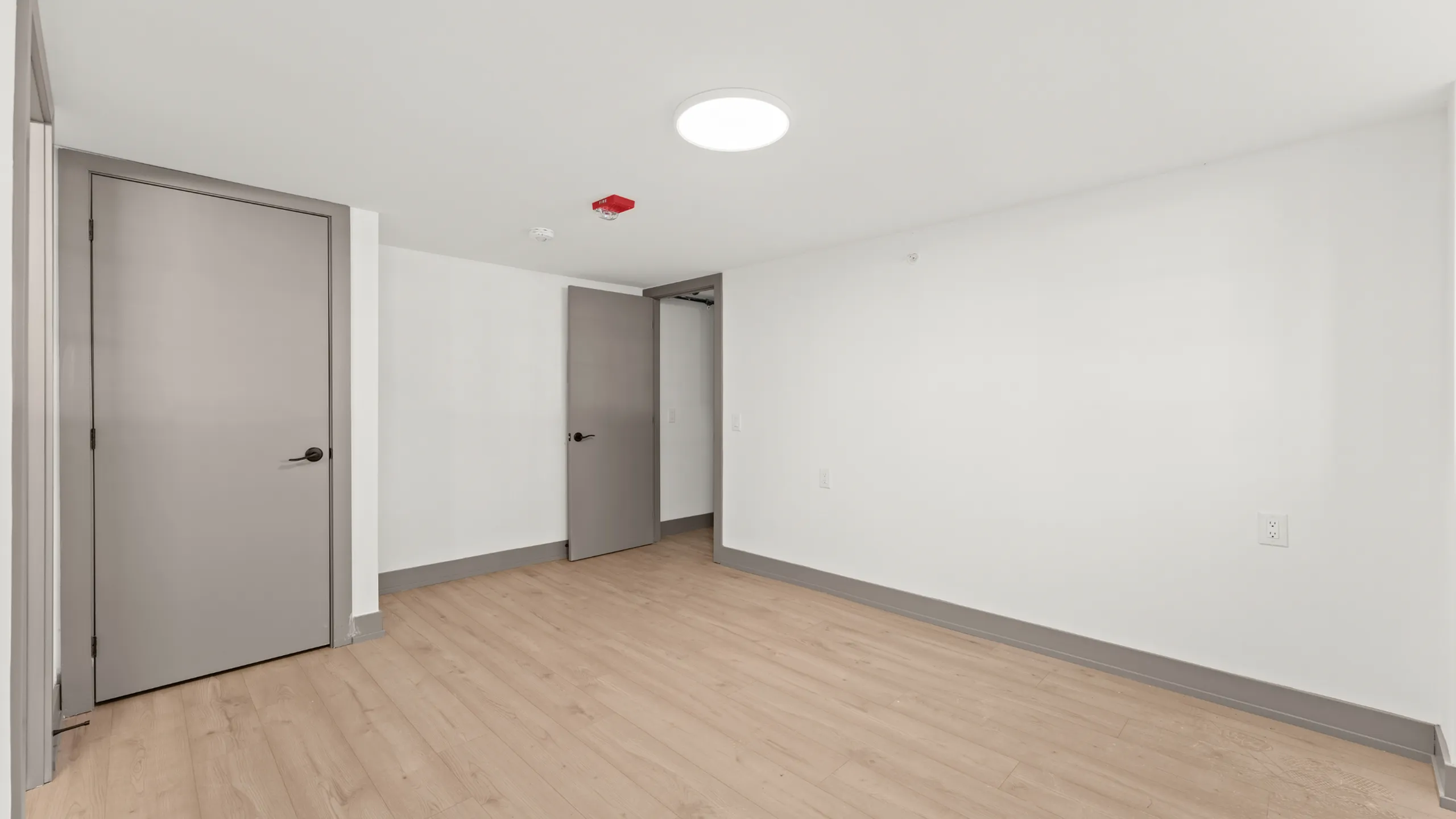 Bright and modern room with sleek wooden flooring and neutral-toned doors, ideal for a cozy bedroom or efficient office space.