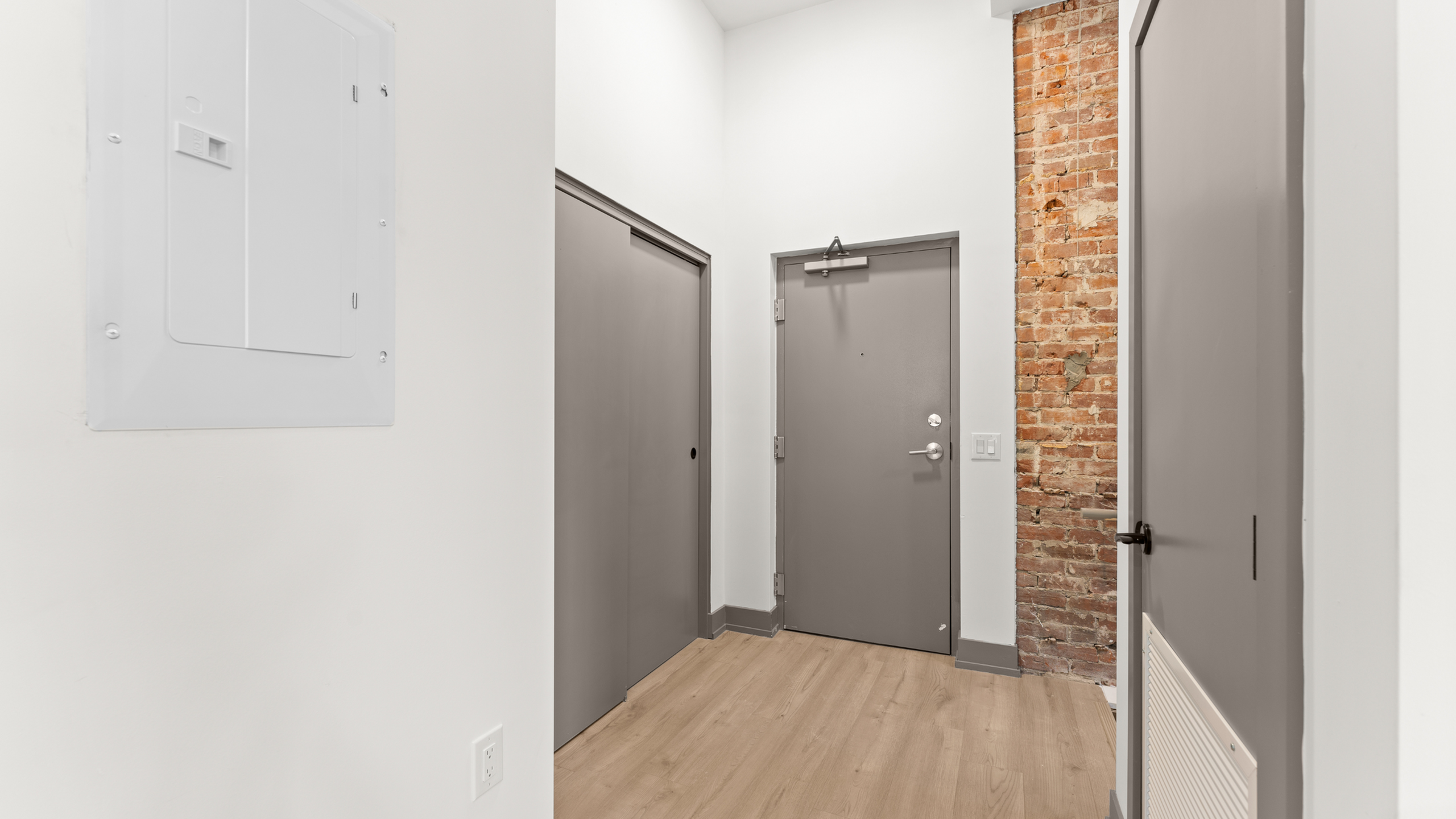 Chic apartment entryway featuring modern doors and a stylish exposed brick accent wall.
