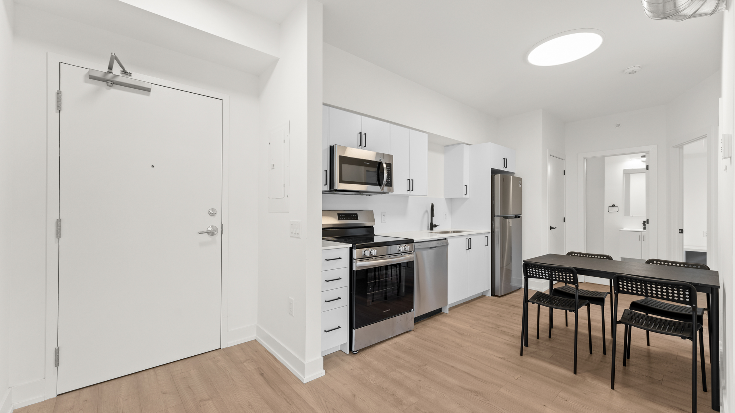 Modern kitchen and dining area with sleek appliances and minimalistic decor, offering a bright and inviting space.