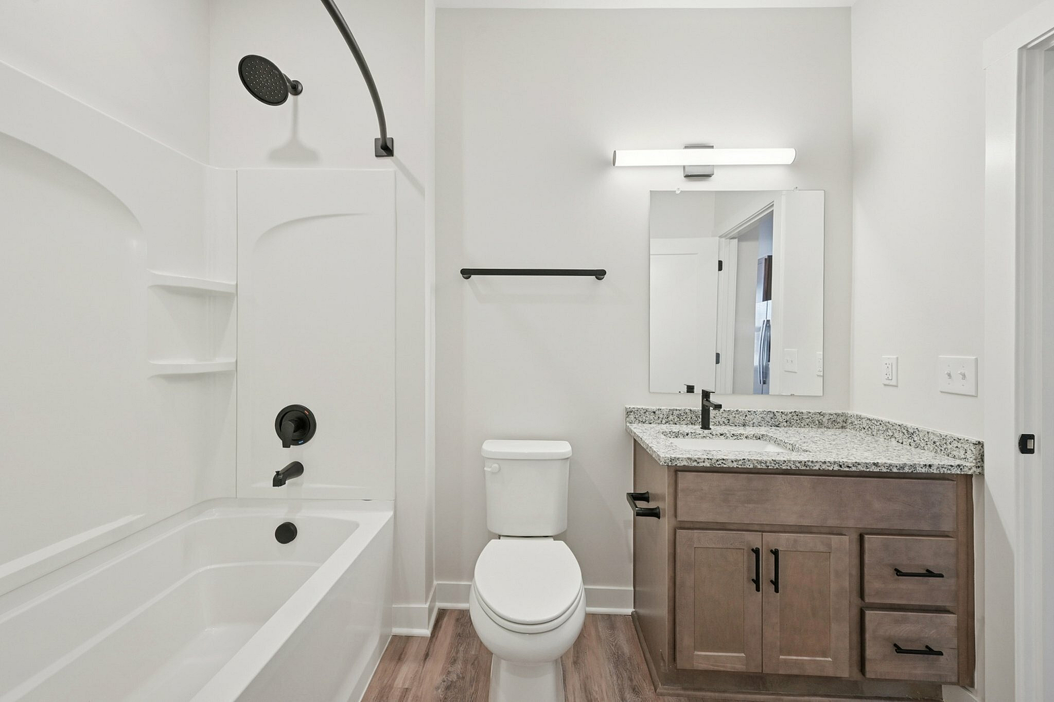 Modern bathroom featuring a sleek white bathtub, elegant granite countertop, and stylish black fixtures.