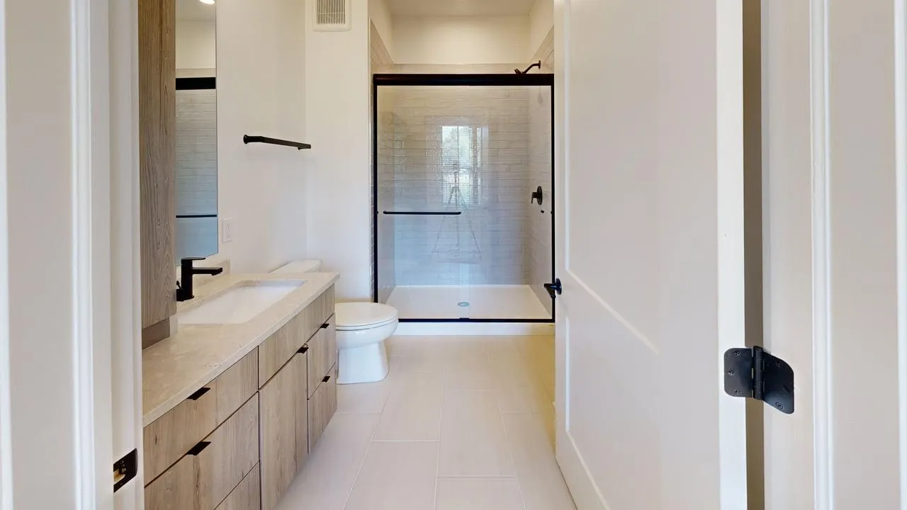 Bright, modern bathroom featuring a stylish wooden vanity, sleek glass-enclosed shower, and elegant fixtures.