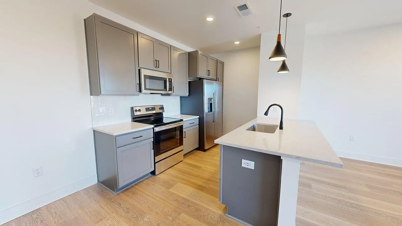 Sleek modern kitchen with stainless steel appliances, stylish pendant lighting, and elegant cabinetry.