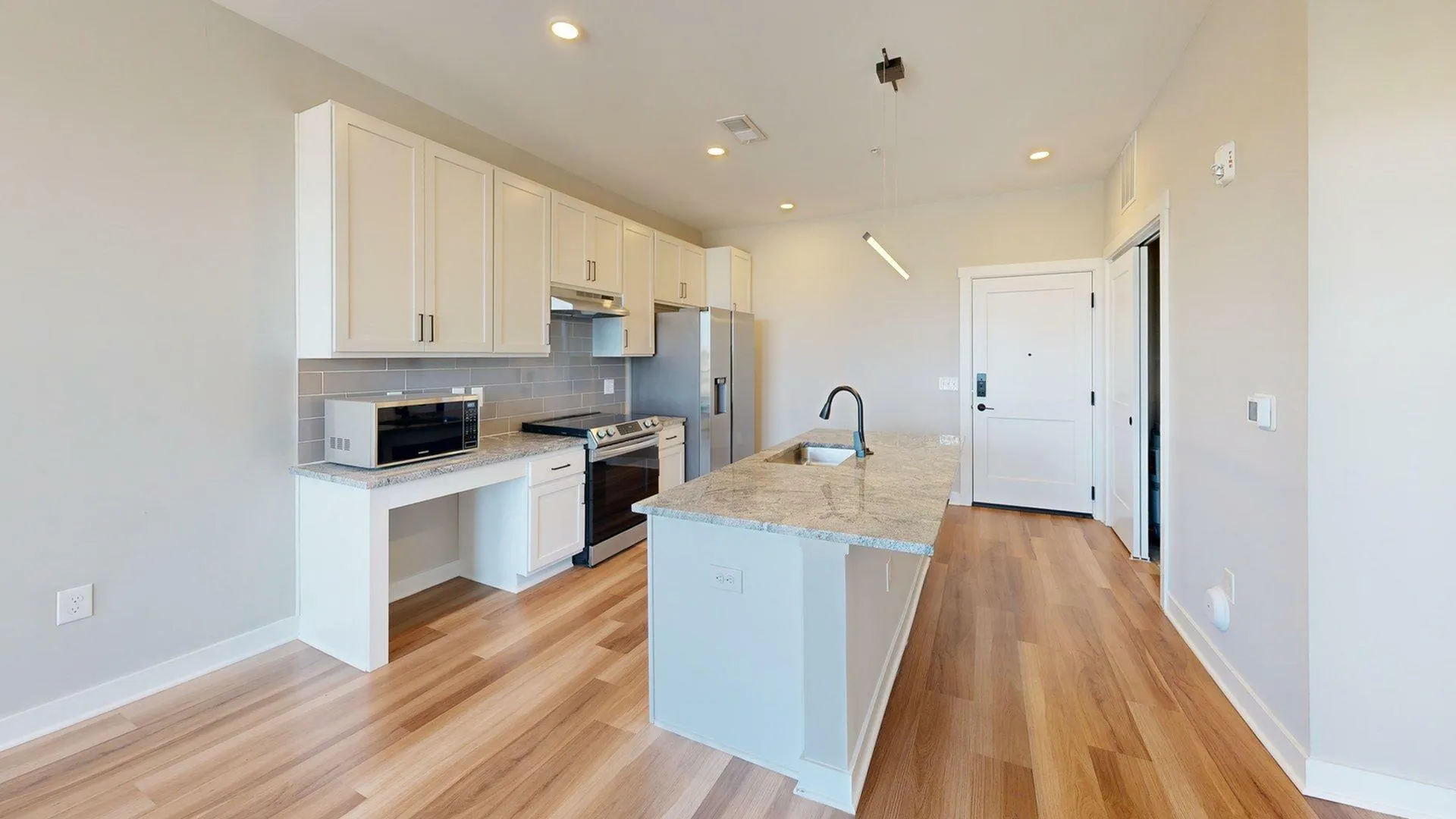 Modern kitchen with elegant countertops, sleek cabinetry, and stainless steel appliances in a well-lit open space.