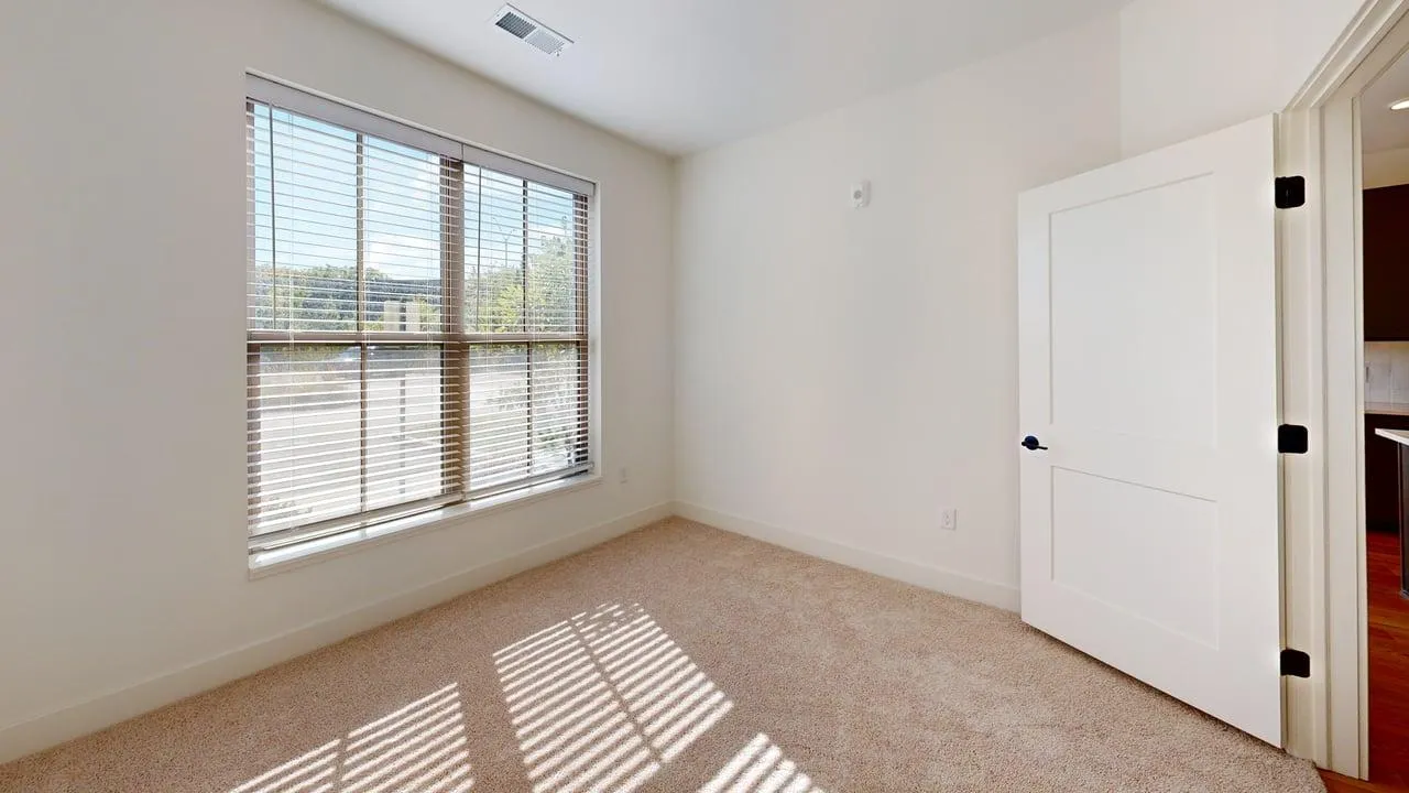 Bright and airy room with large windows and plush carpeting, ideal for a cozy, sunlit space.