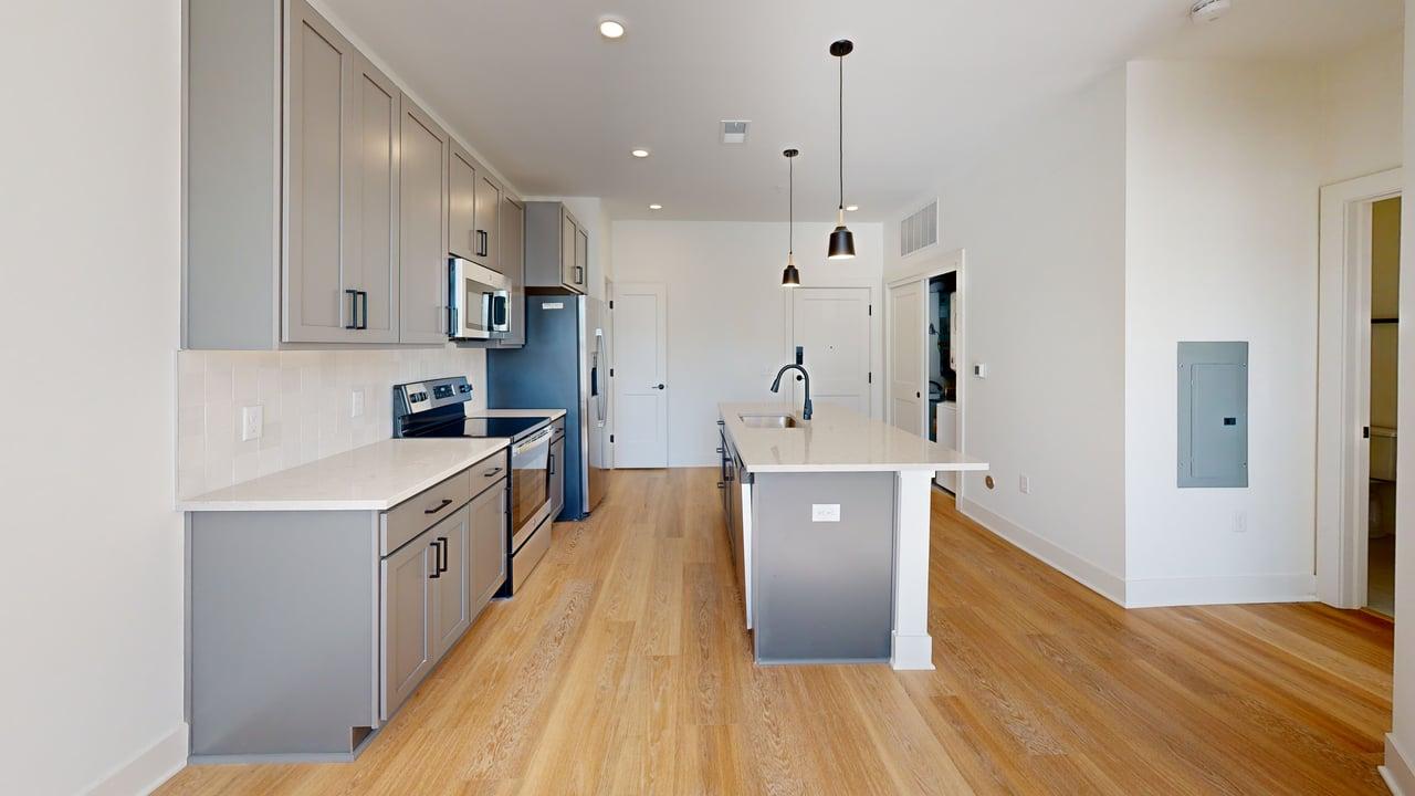 Sleek modern kitchen with stylish gray cabinetry, stainless steel appliances, and a central island with elegant pendant lighting.