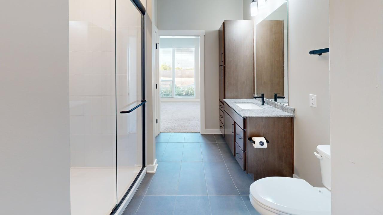 Bright modern bathroom with sleek glass shower, elegant vanity, and large window offering natural light.