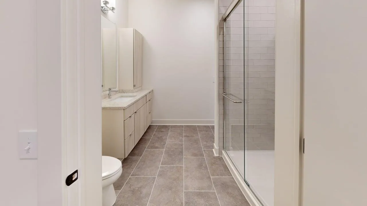Elegant bathroom with modern fixtures, spacious glass shower, and sleek vanity featuring ample storage.