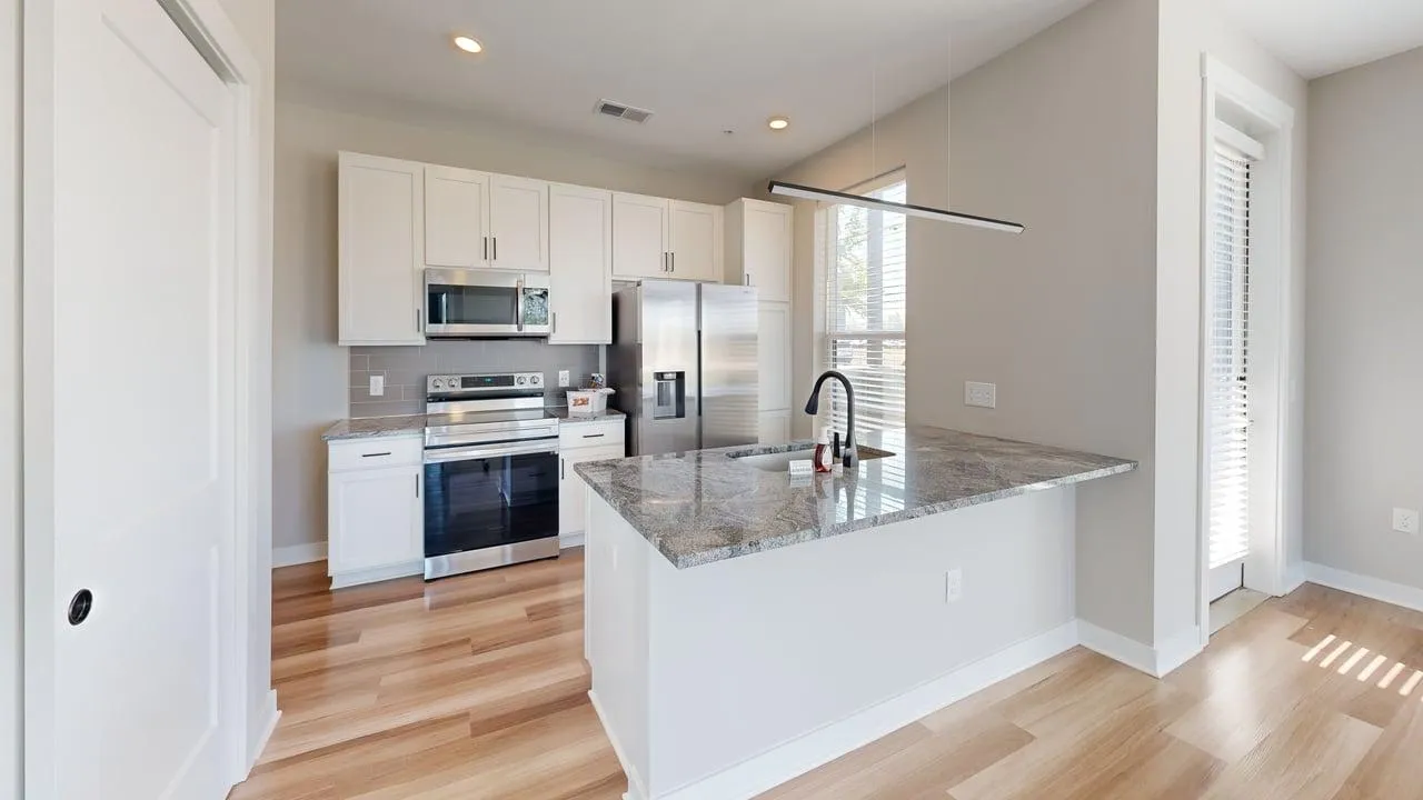 Modern kitchen with sleek stainless steel appliances, elegant gray countertops, and contemporary white cabinetry. Bright and inviting with ample natural light.