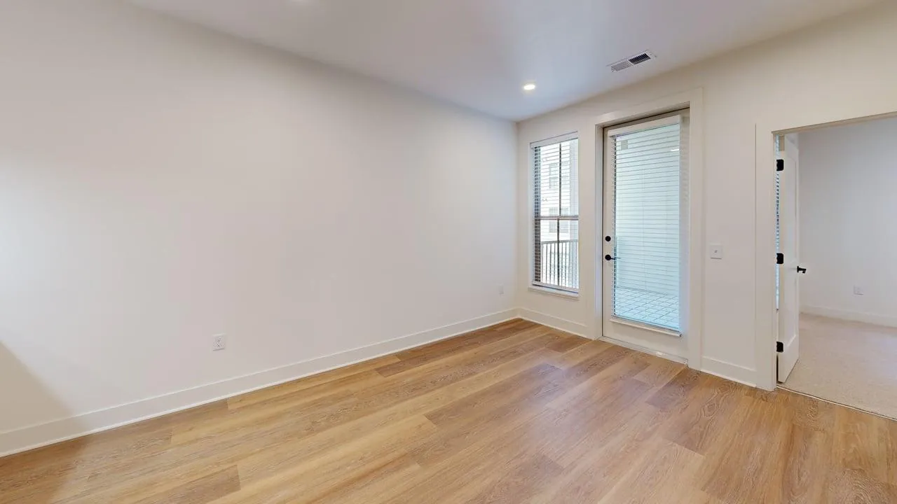 Bright and spacious room with elegant wood flooring and large windows offering natural light, perfect for a modern lifestyle.