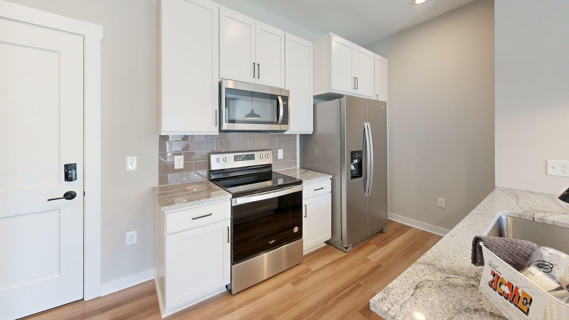 Modern kitchen with sleek stainless steel appliances, granite countertops, and elegant white cabinetry.